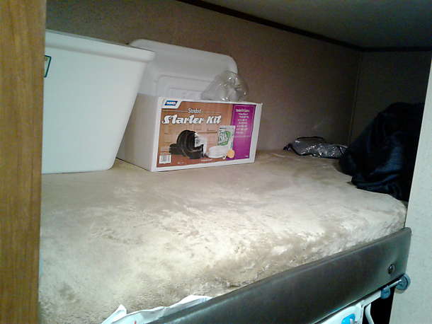 parked next to a building with electrical hookups at night.|This compact RV rental bathroom features a toilet and a small bathtub with a shower