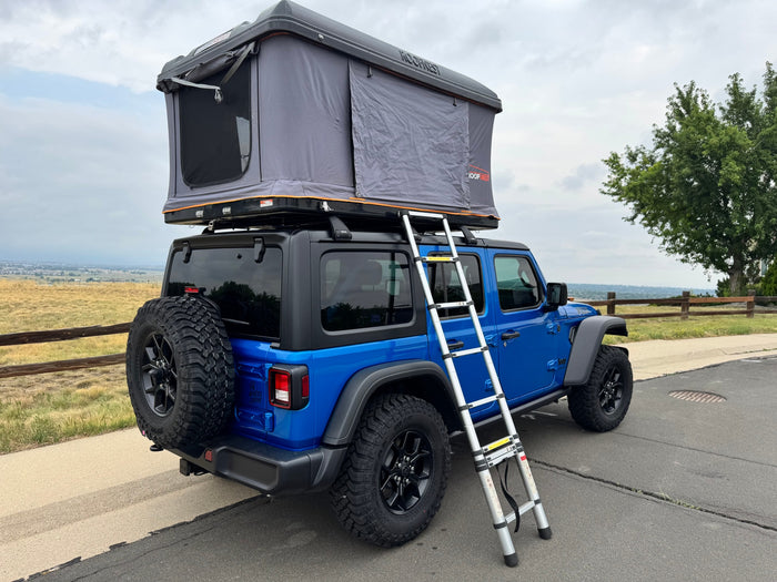 Blue Jeep Wrangler with a Roofnest rooftop tent, offering a unique RV rental camping experience.