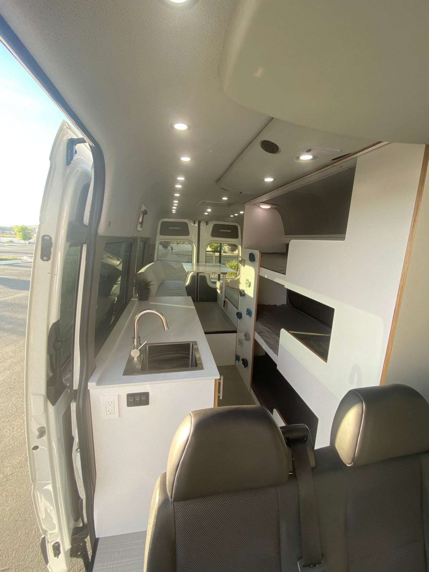 Spacious RV rental interior with kitchen, bunk beds, and dining area, offering comfortable mobile living.