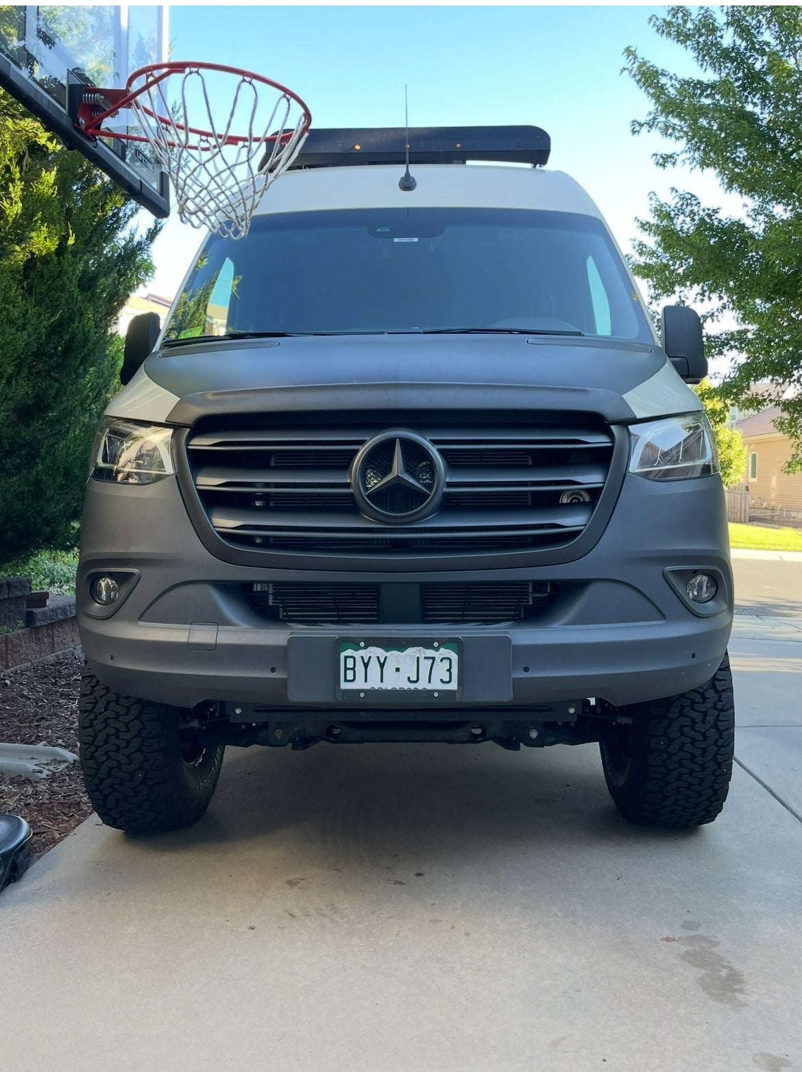 Front of a rugged grey Mercedes Sprinter rv rental van, parked by a hoop, ready for adventure.