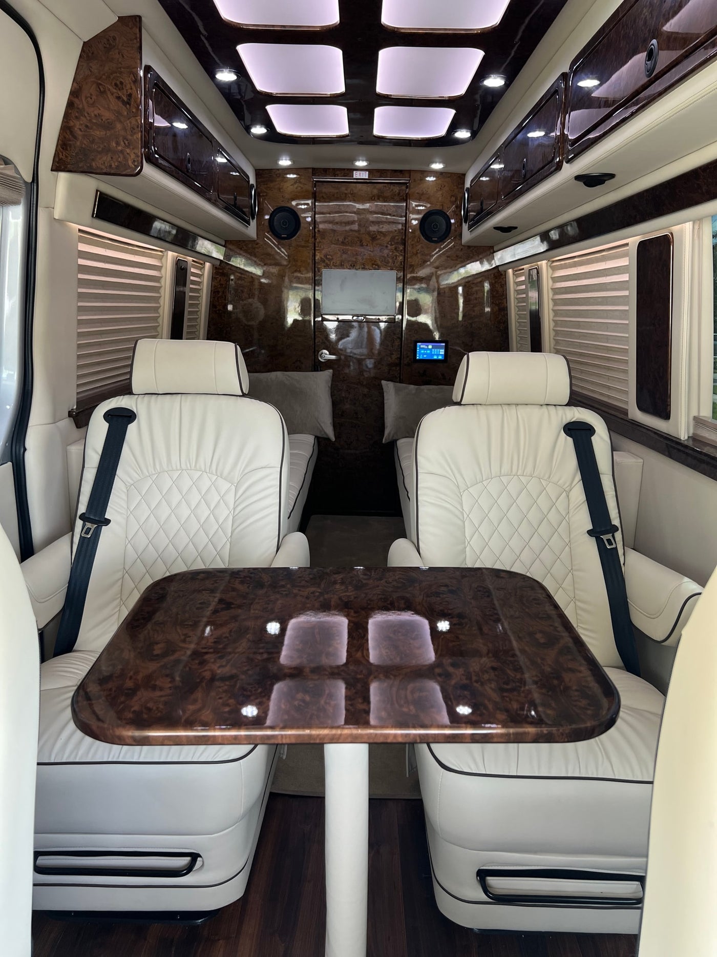 and a spacious rear lounge area.|Luxury RV rental interior: white leather captain's chairs — photo 5