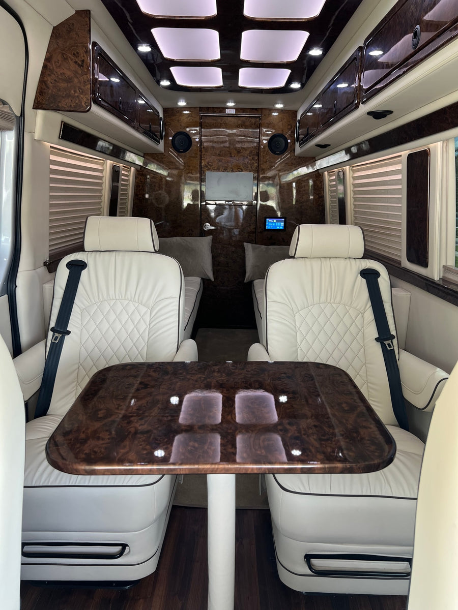 and a spacious rear lounge area.|Luxury RV rental interior: white leather captain's chairs