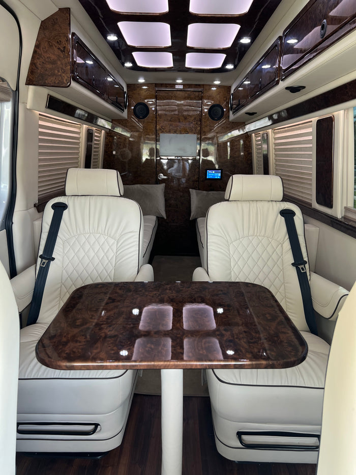 and a spacious rear lounge area.|Luxury RV rental interior: white leather captain's chairs