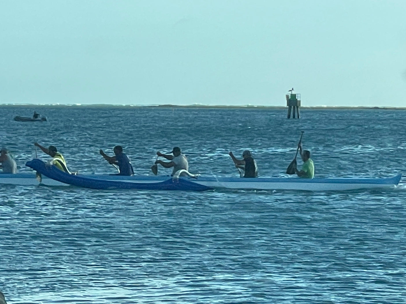 Paddlers in an outrigger canoe glide on the water. Explore nature's beauty, maybe even with an RV rental.