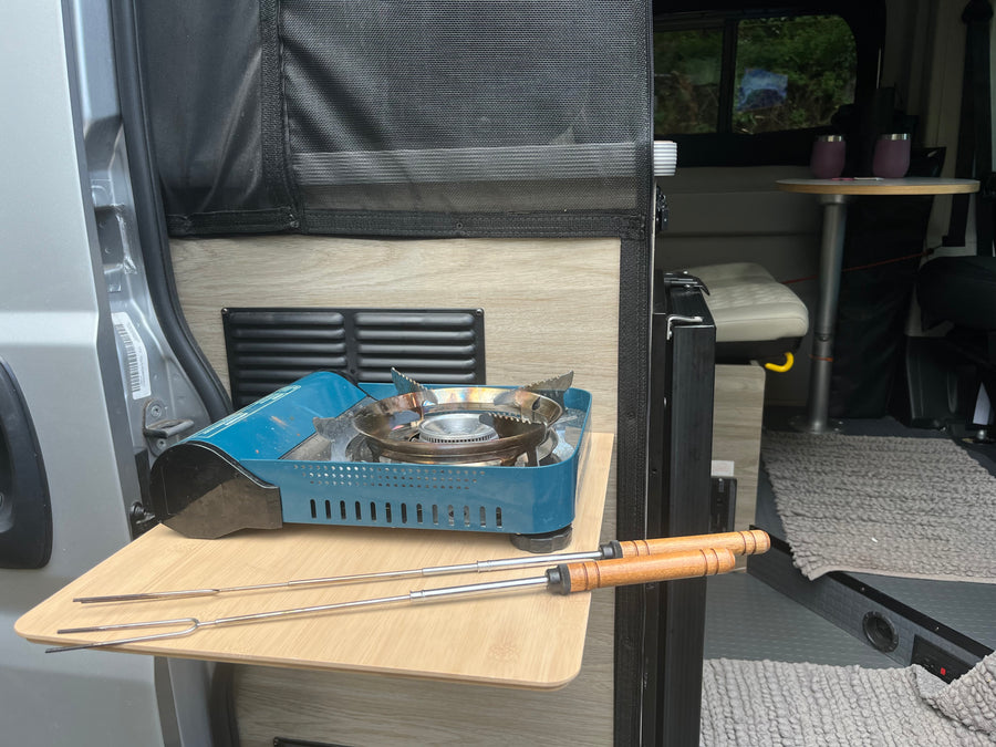 An RV rental's clever pull-out kitchen with a portable gas stove and roasting sticks, ready for camp meals.