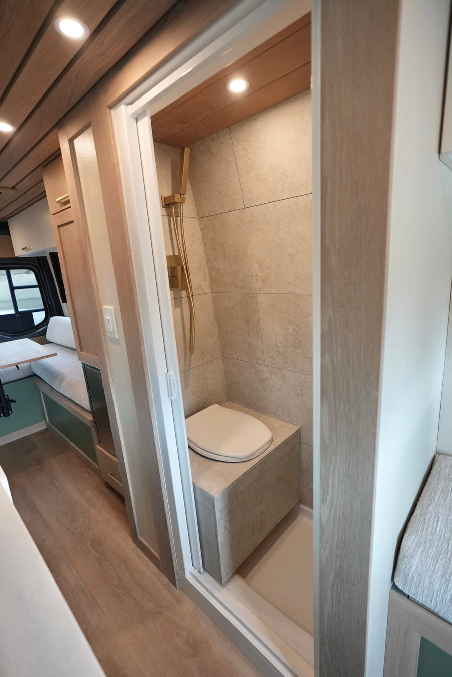 revealing a bright custom interior with wood details and green accents. Perfect RV rental.|Explore a stylish RV rental's interior: modern kitchen