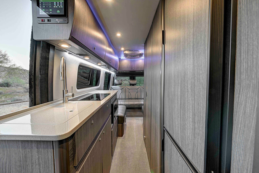 Modern rv rental interior: kitchen with smart panel, sleek overhead storage, and cozy rear seating, ideal for travel.