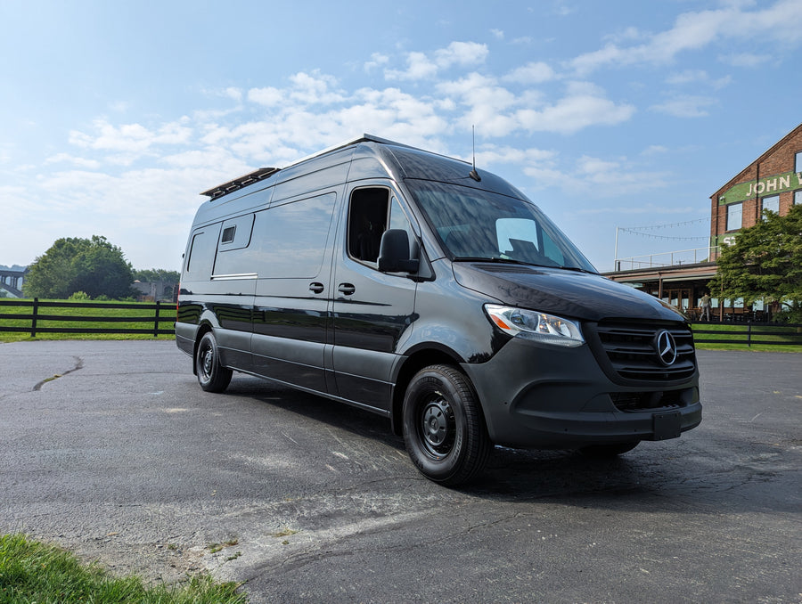 Sleek black Mercedes Sprinter camper van RV rental parked outdoors, ready for adventure.
