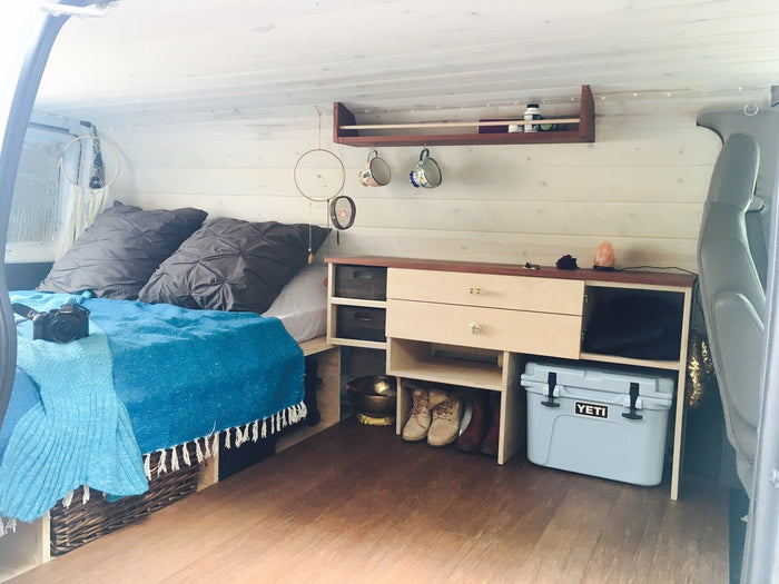 preparing for an outdoor road trip adventure.|Cozy RV rental interior featuring a bed with blue blankets