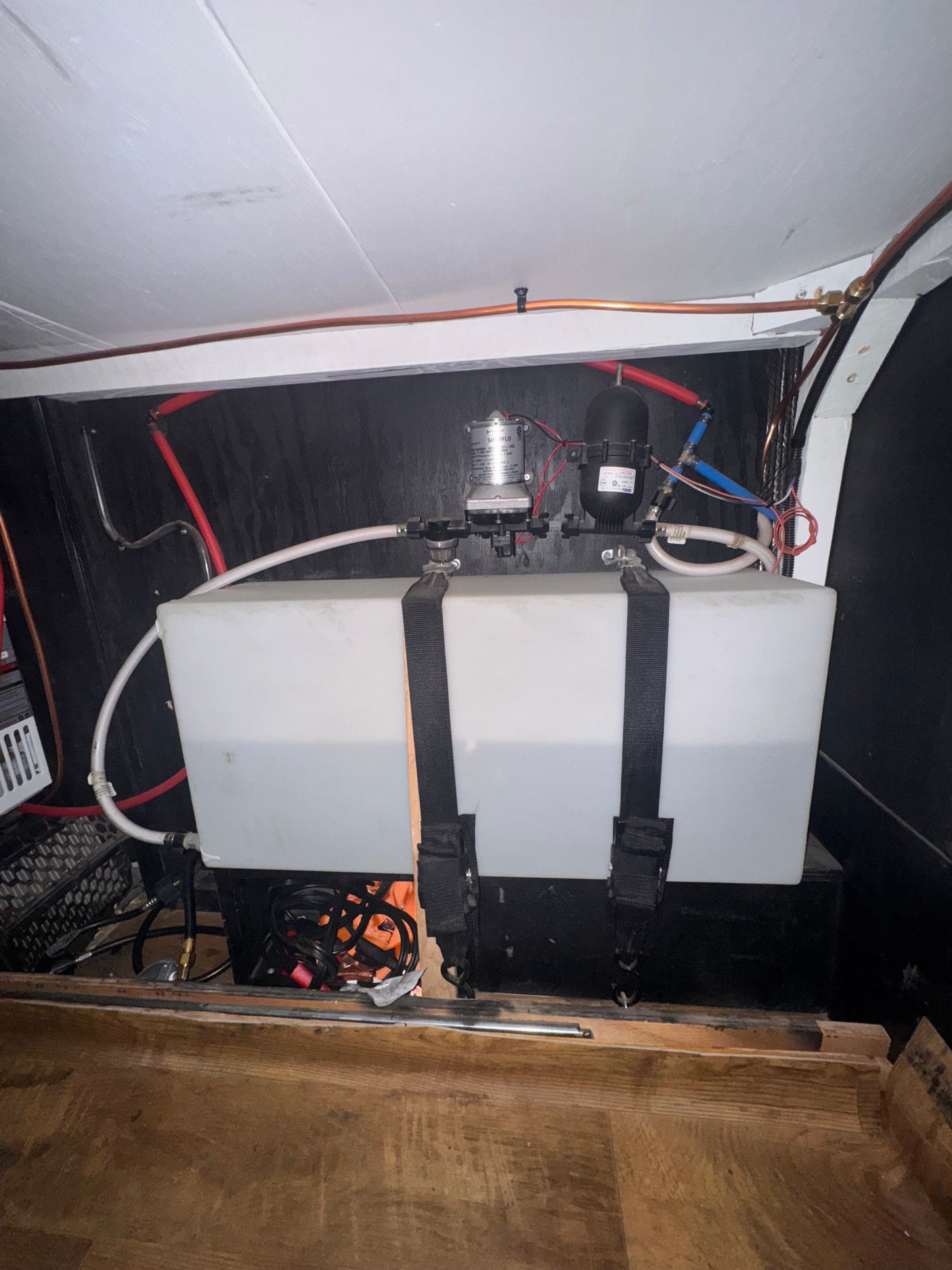 RV rental water system: Two translucent tanks, a SHURFLO pump, and PEX plumbing lines visible in a compact setup.