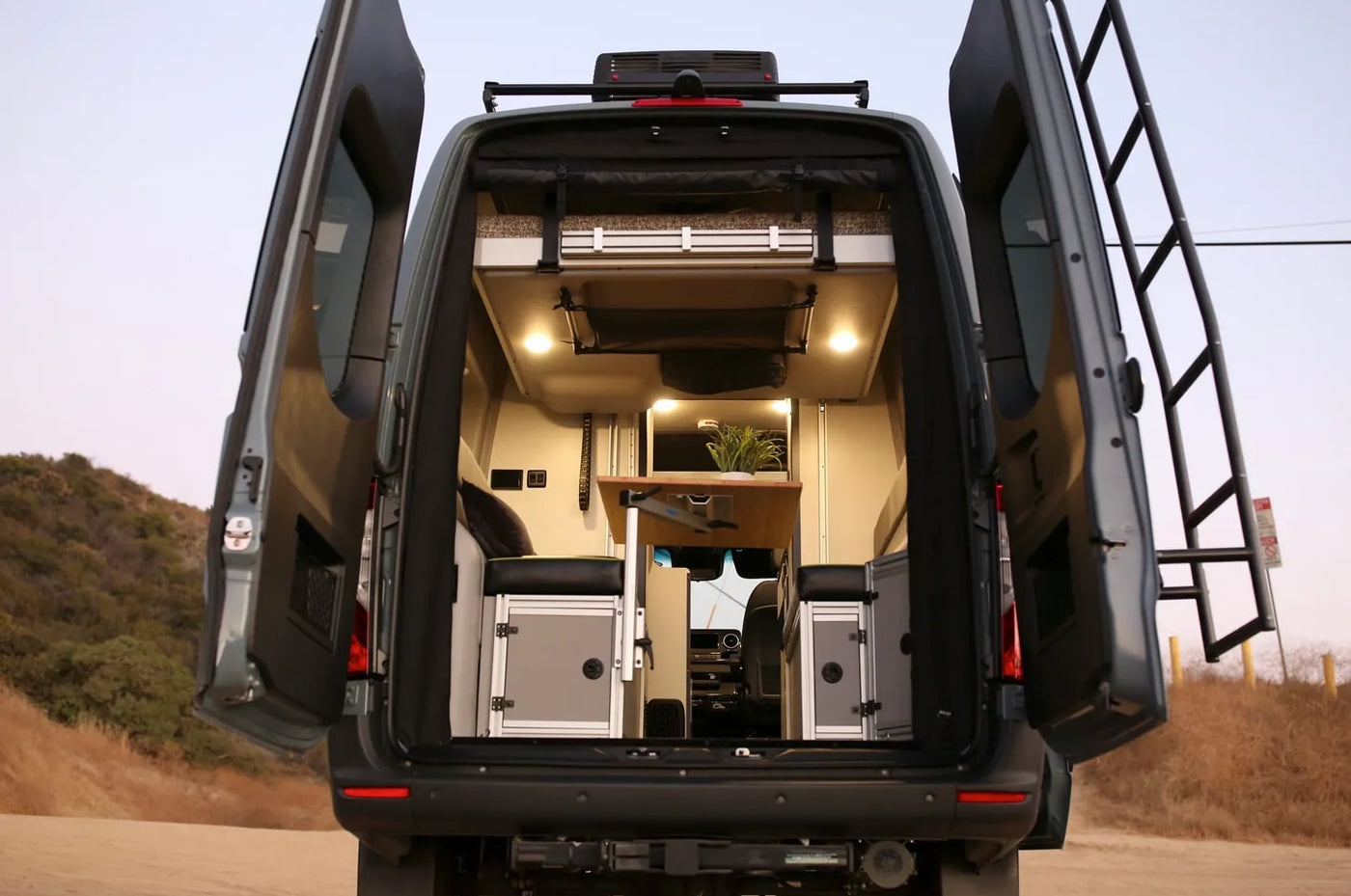Rear view of an RV rental camper van, doors open, revealing a cozy, functional interior with a bed & table. — photo 9