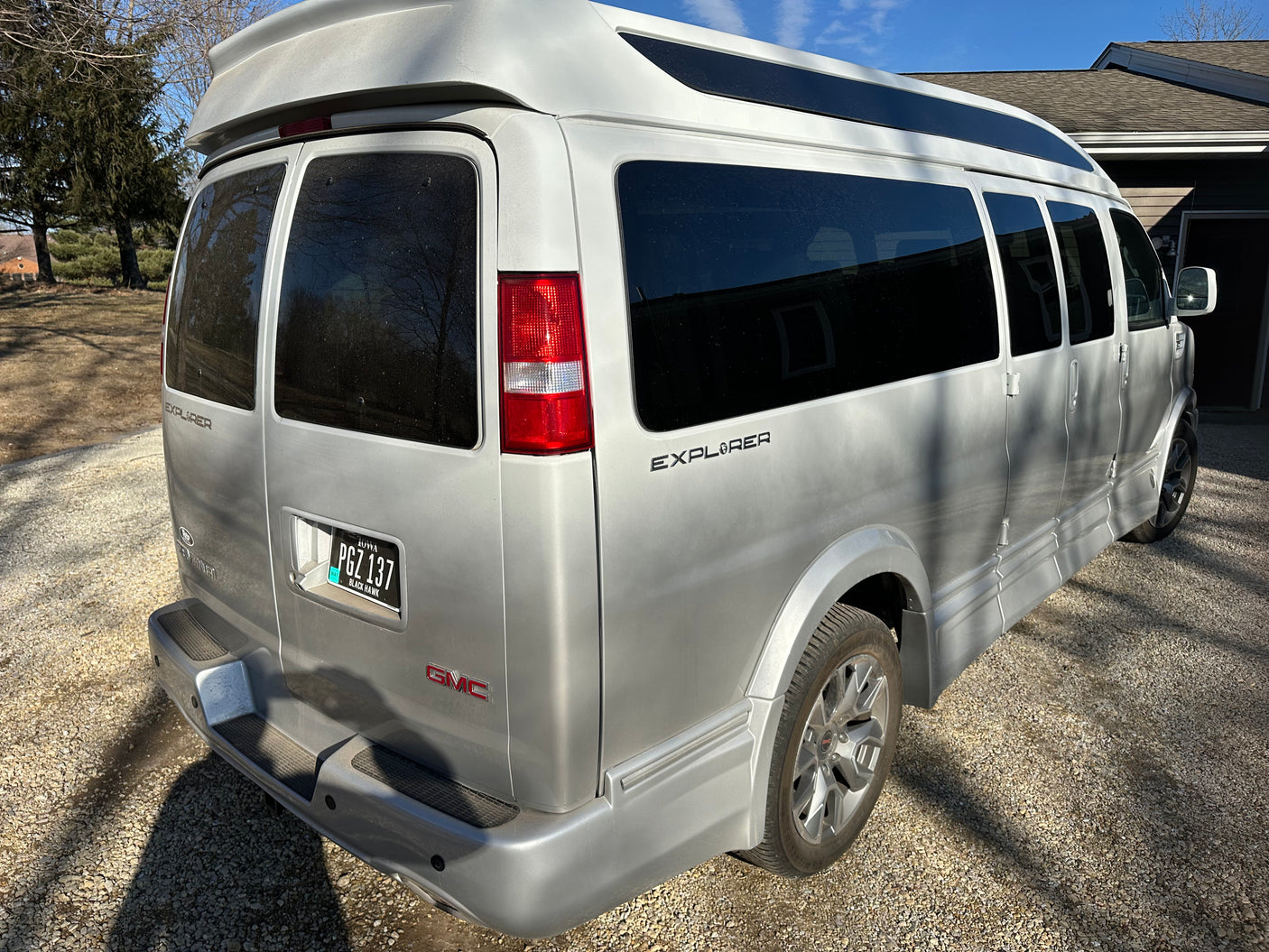 Silver GMC Explorer conversion van, an RV rental. Parked on gravel, ideal for your travels.