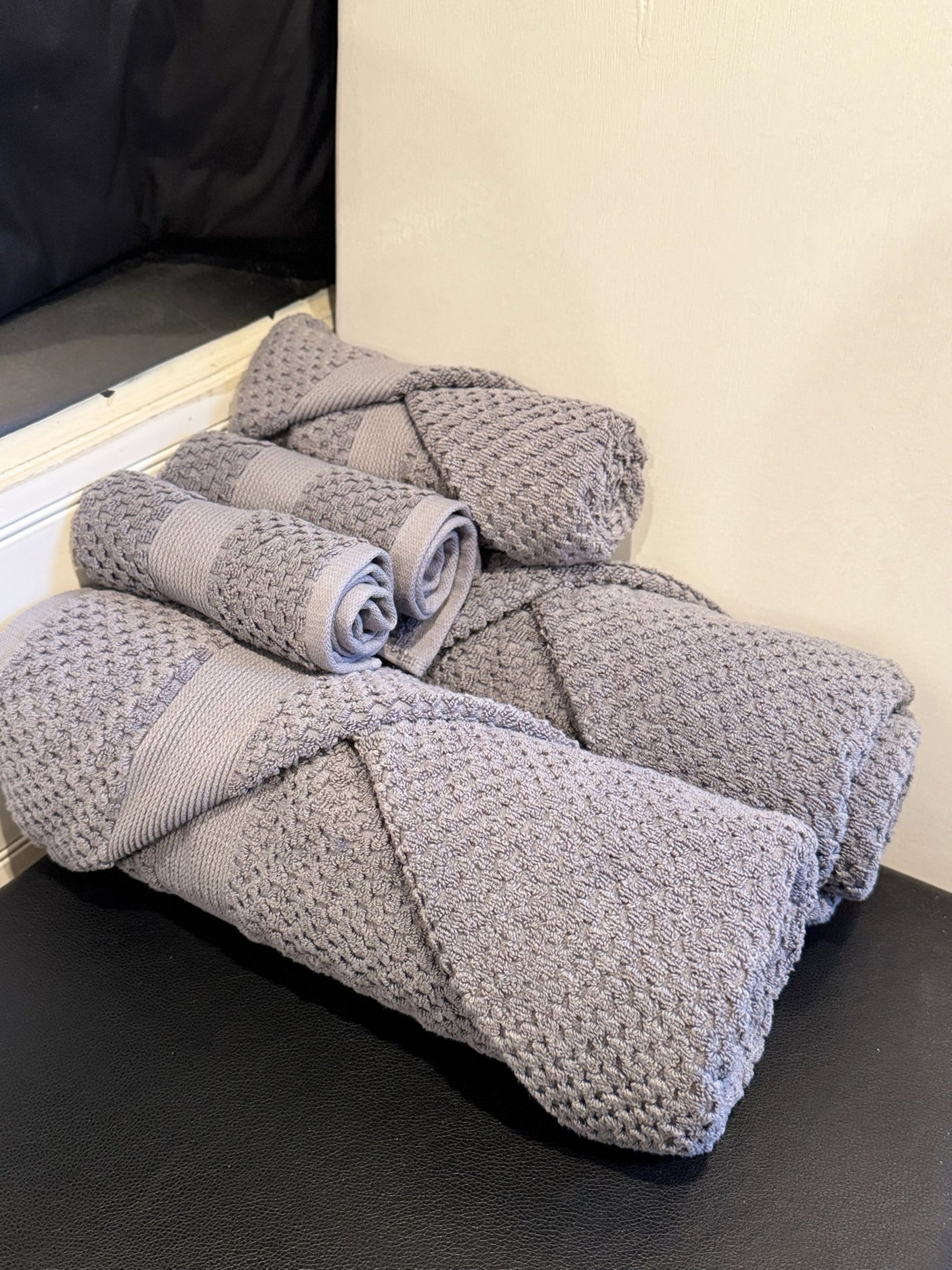 Neatly rolled grey towels on a black surface, ready for your RV rental. Experience comfort and essential amenities on the road.