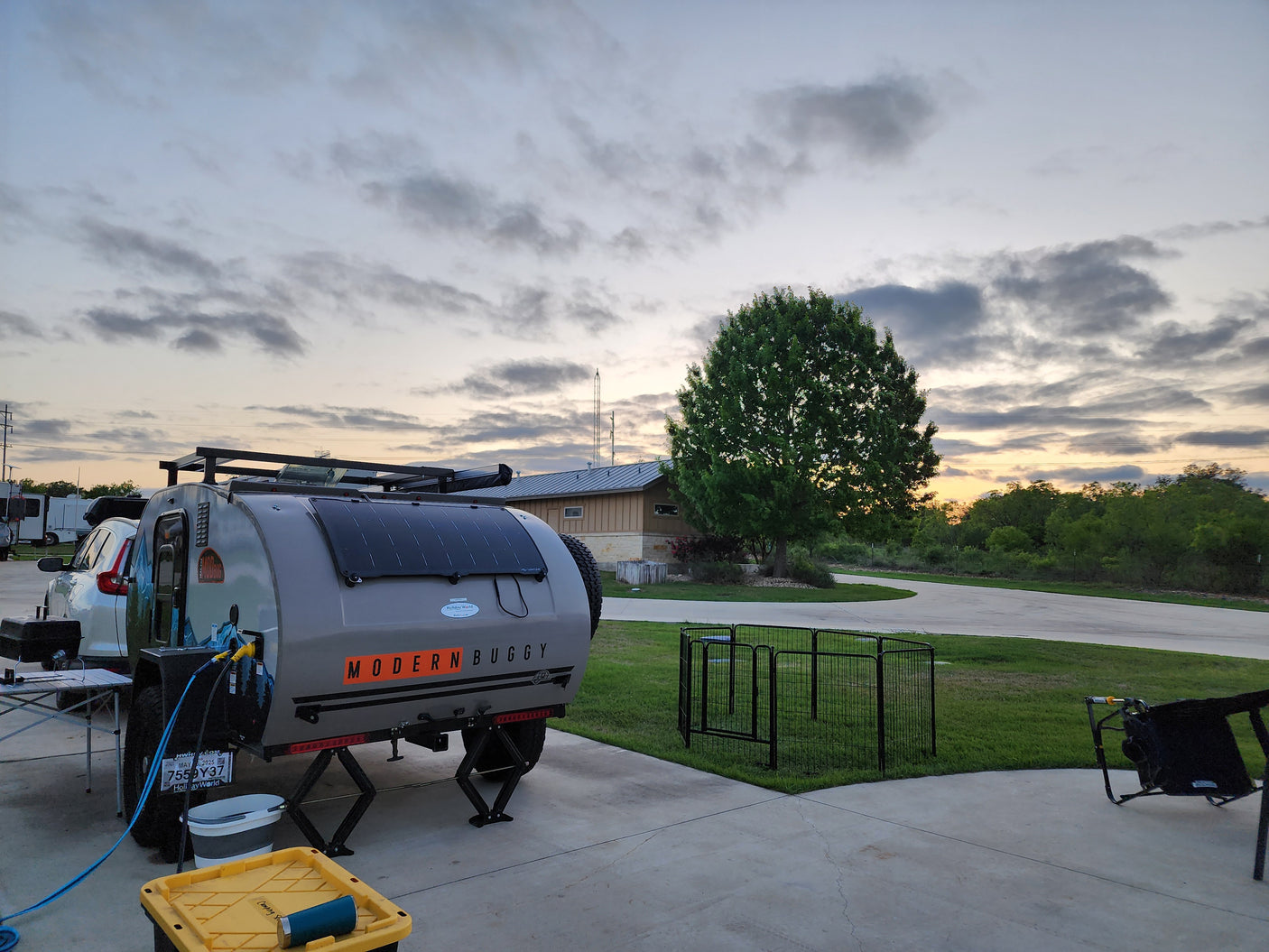 RV rental: A Modern Buggy teardrop trailer with solar panels is set up at a campsite with a pet pen.