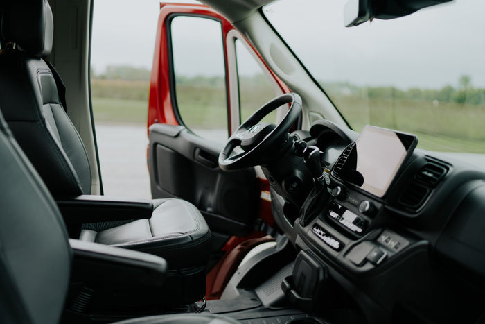 Experience comfort in our RV rental! View of the spacious interior cab, featuring black leather driver's seat & modern dash.