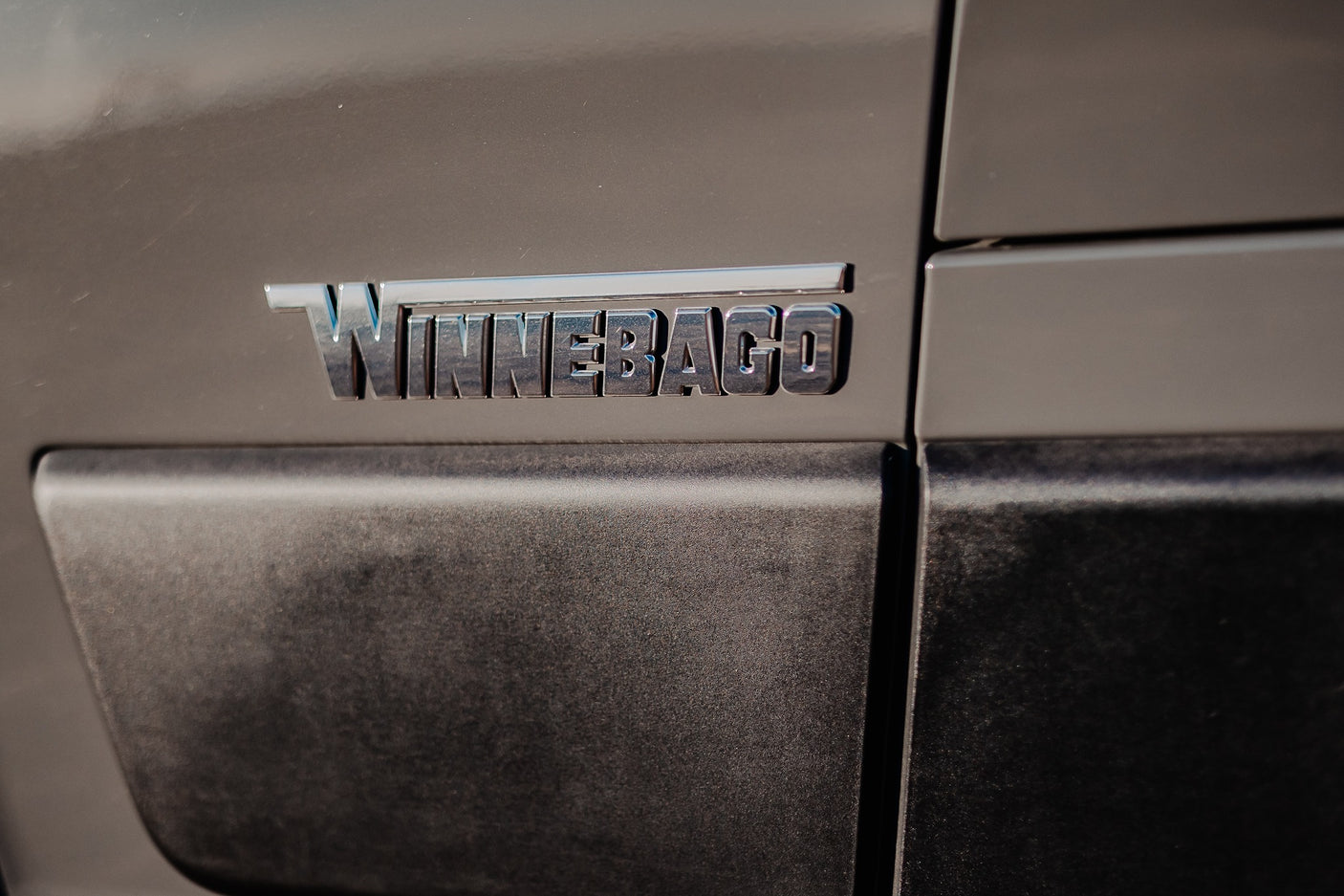 The metallic 'WINNEBAGO' emblem on the side of a modern RV, ready for your next rv rental adventure.