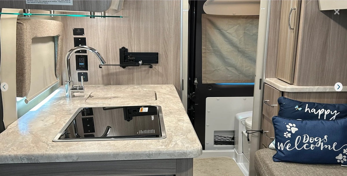 and a glimpse of the compact toilet area.|Cozy RV rental interior shows gray seating — photo 6