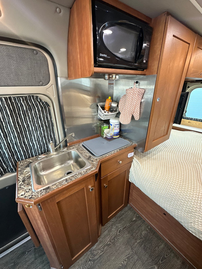 is parked outdoors on a sunny day.|Efficient RV rental interior: cozy kitchen area with sink