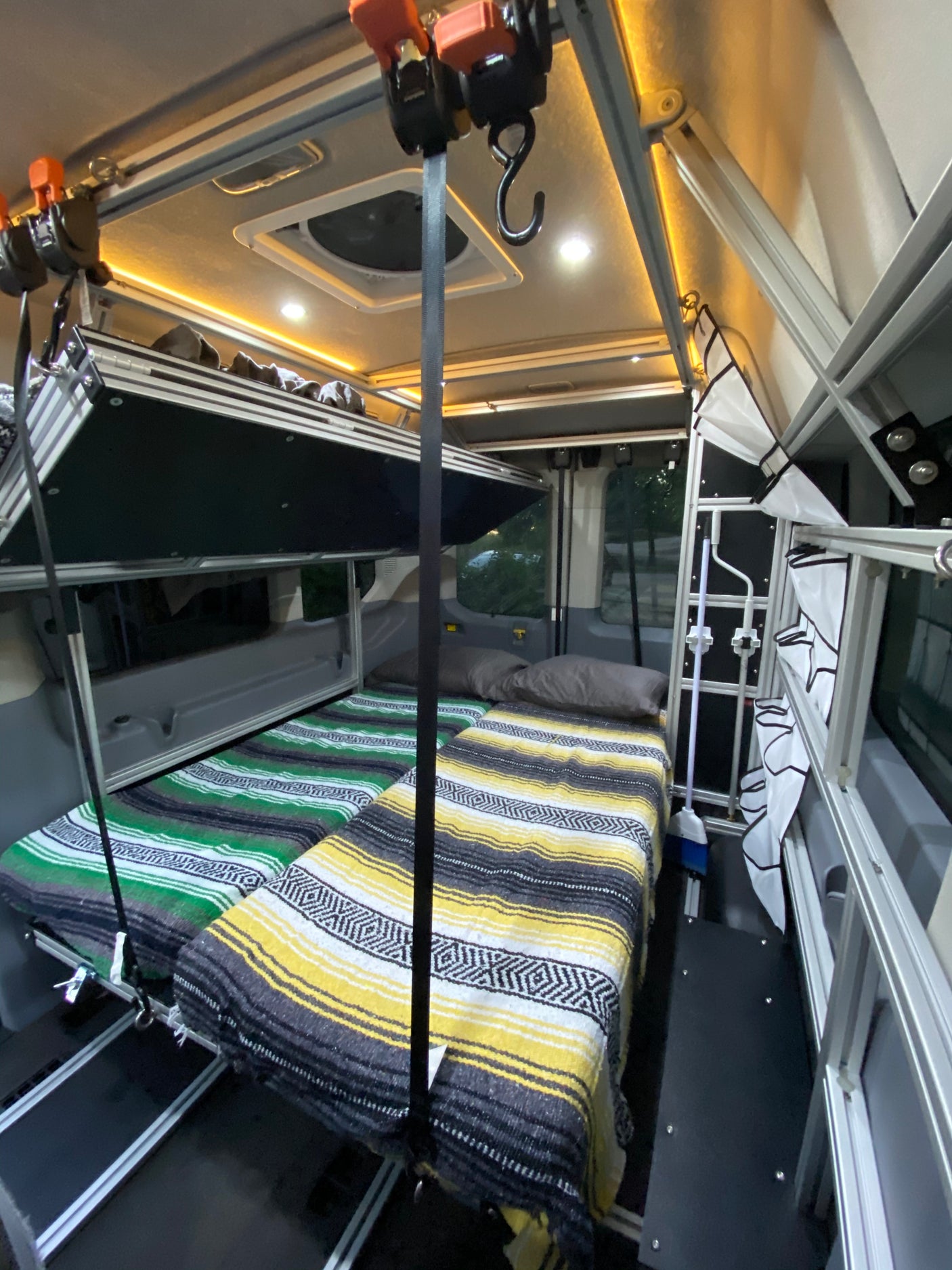 Inside an RV rental: a flexible sleeping setup with a retractable upper bunk and two lower beds, ideal for adventure.