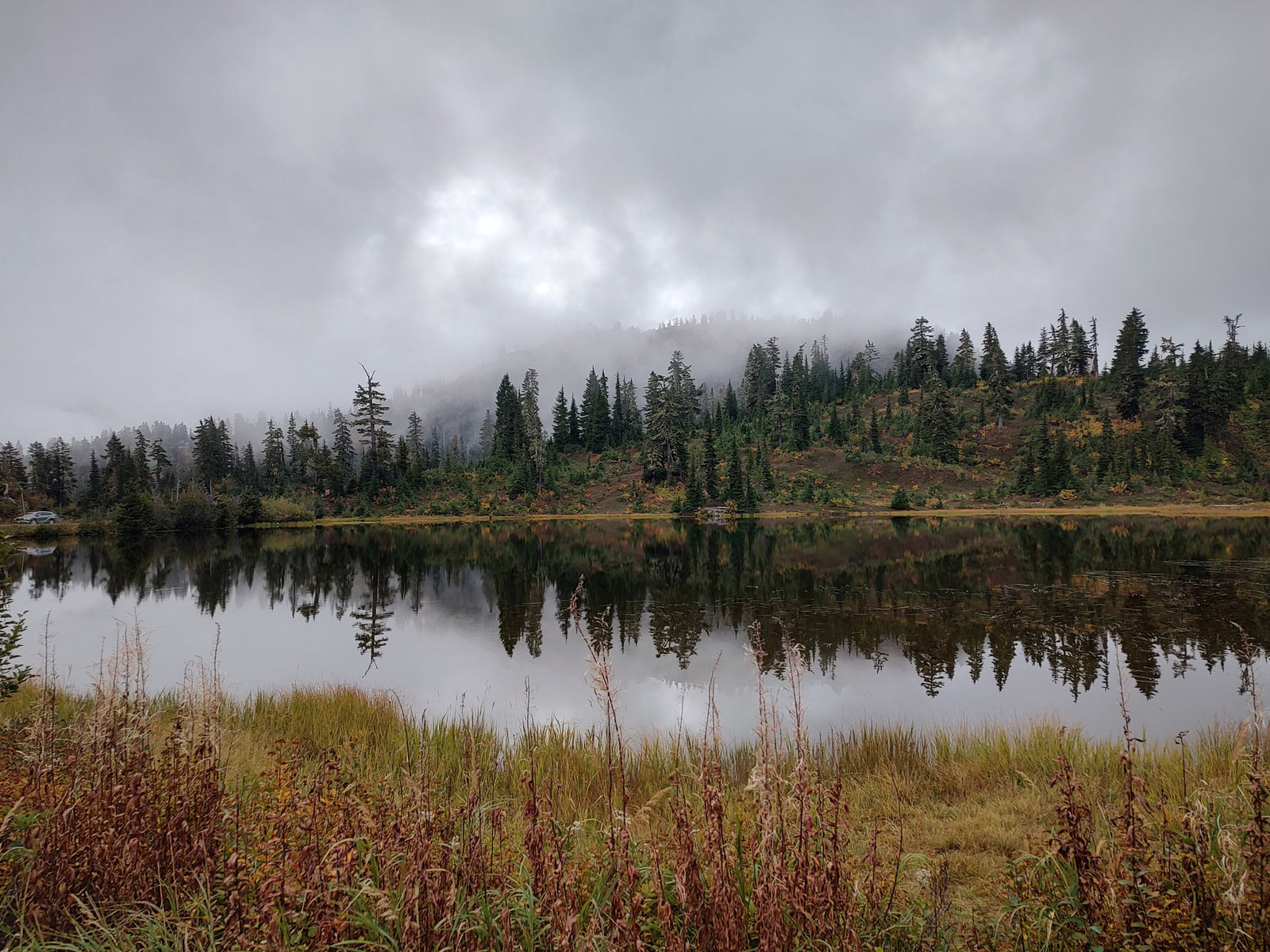 Experience tranquil autumn nature from your RV rental. Misty forest reflects on a calm lake, perfect for outdoor escapes.