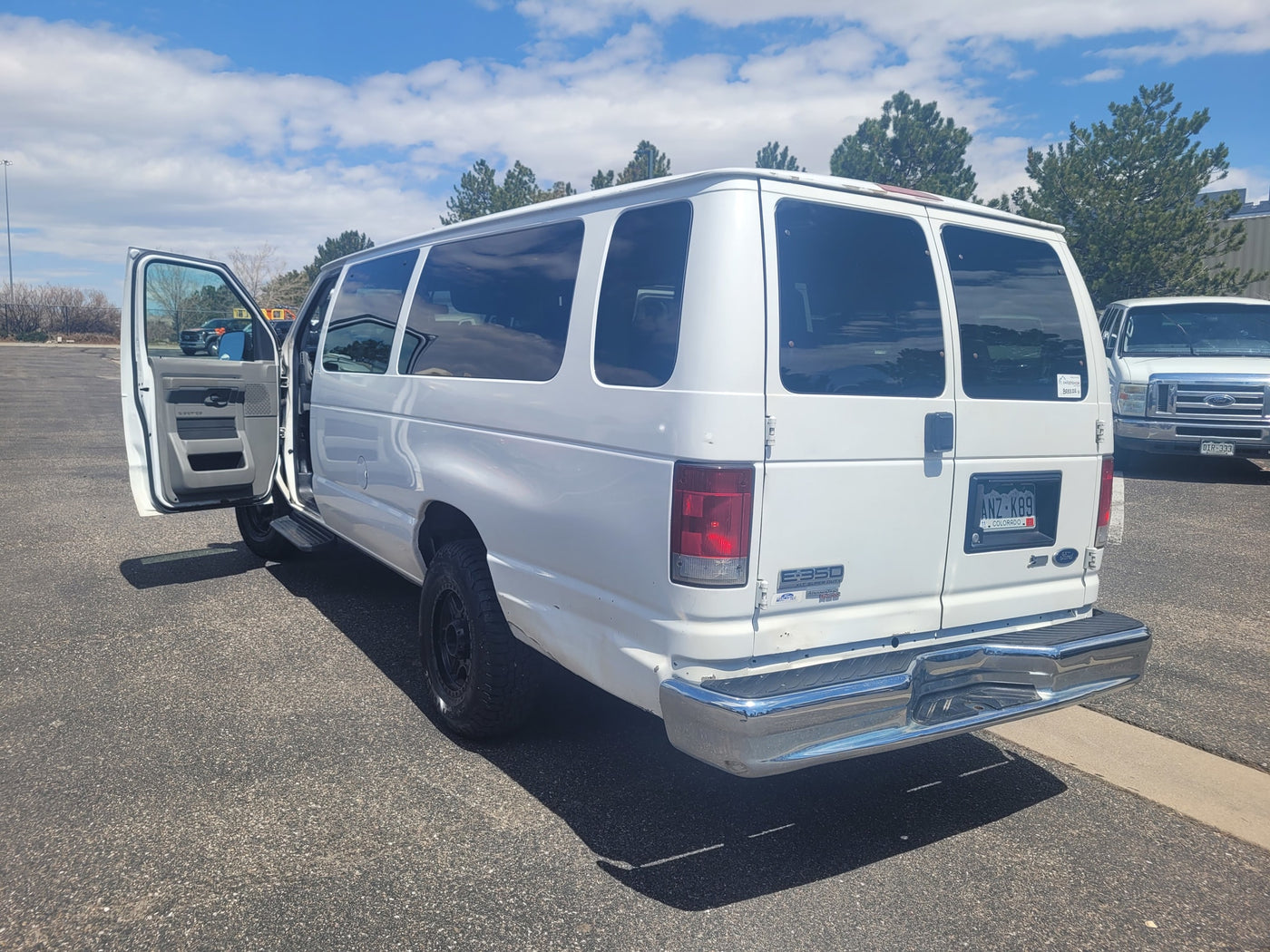 A white Ford E-350 passenger van with its door open. A versatile option for your next rv rental adventure. — photo 2
