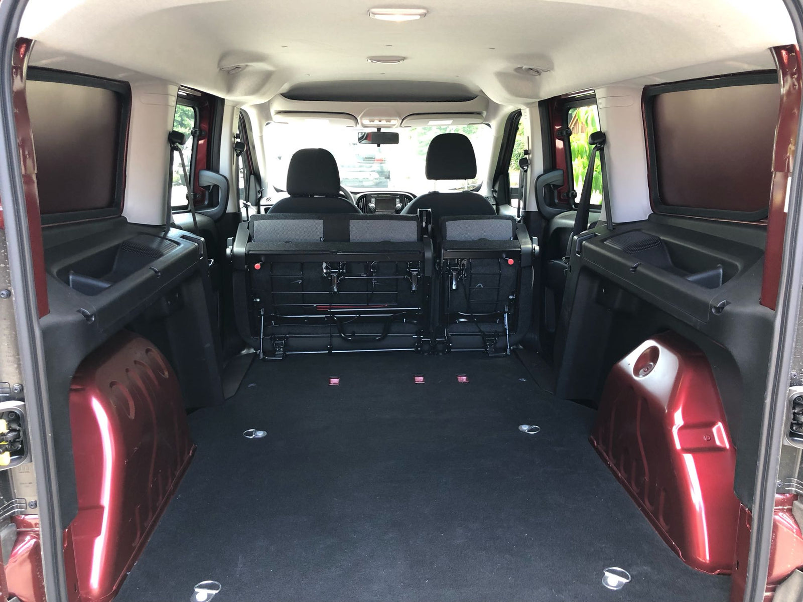 RV rental's spacious rear cargo area: folded seats, flat black floor, red interior panels, and tie-down points.