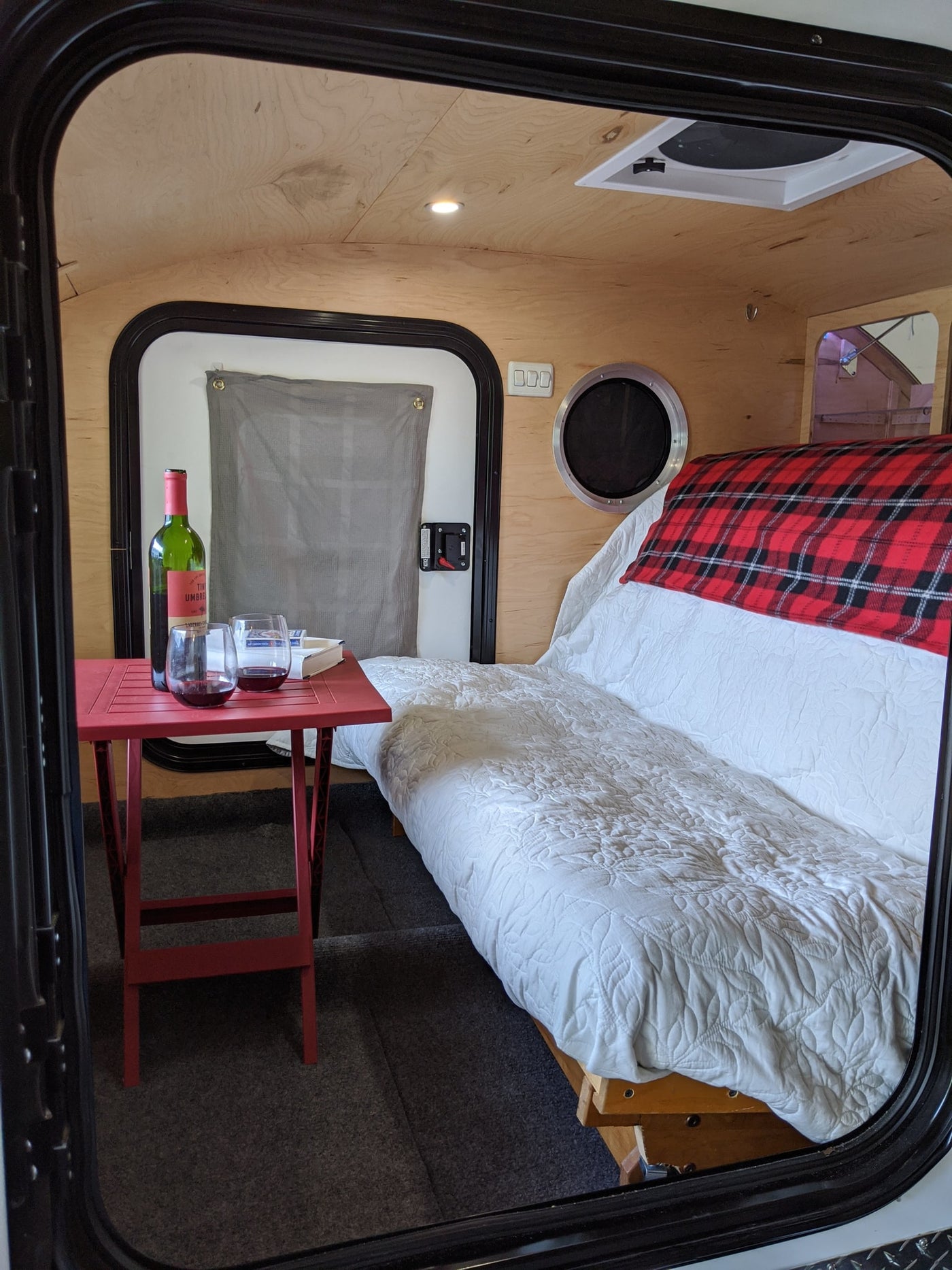 and porthole window.|RV rental interior: a comfy bed with red plaid blanket — photo 6