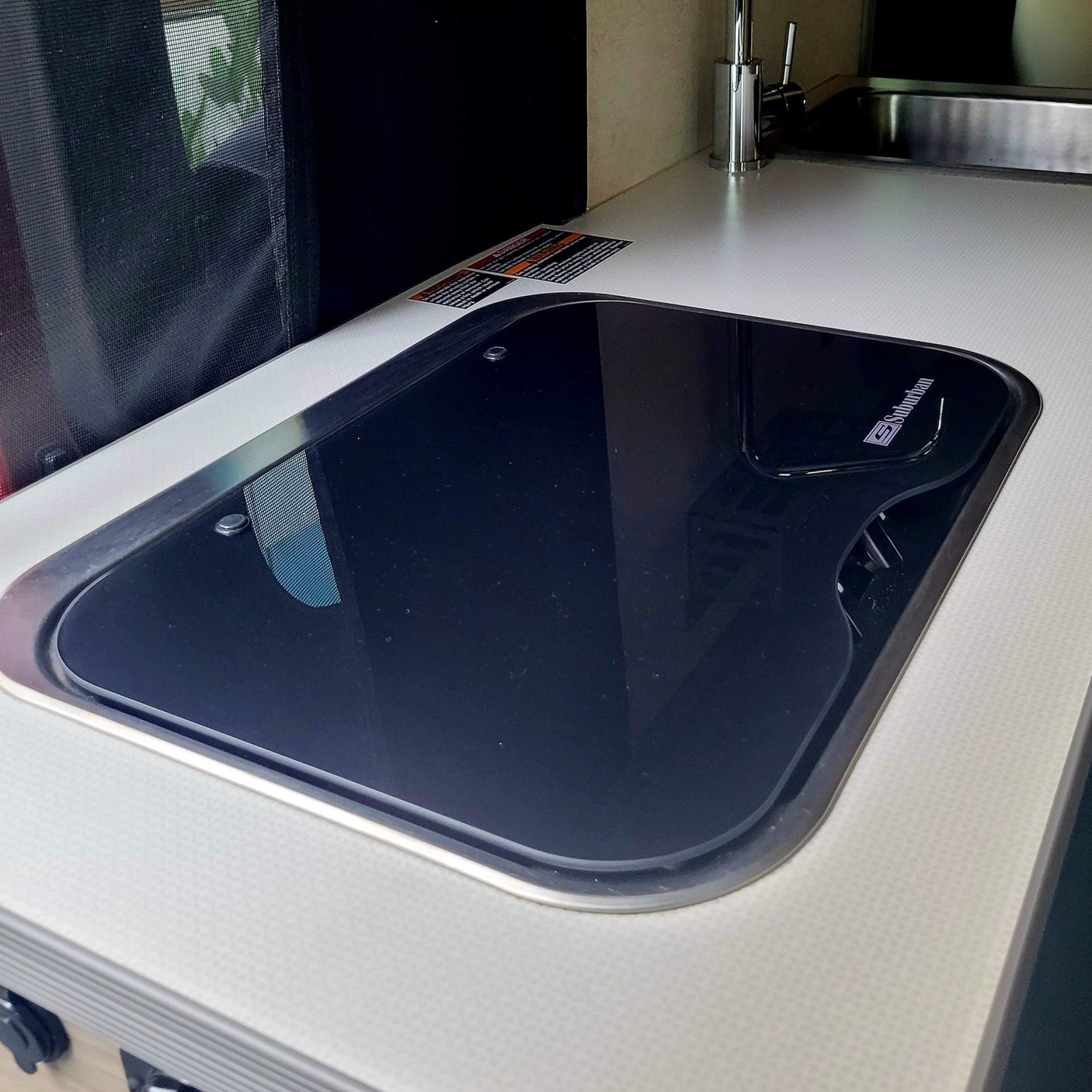 Your RV rental features a clean kitchen with a glass Suburban cooktop and stainless sink.