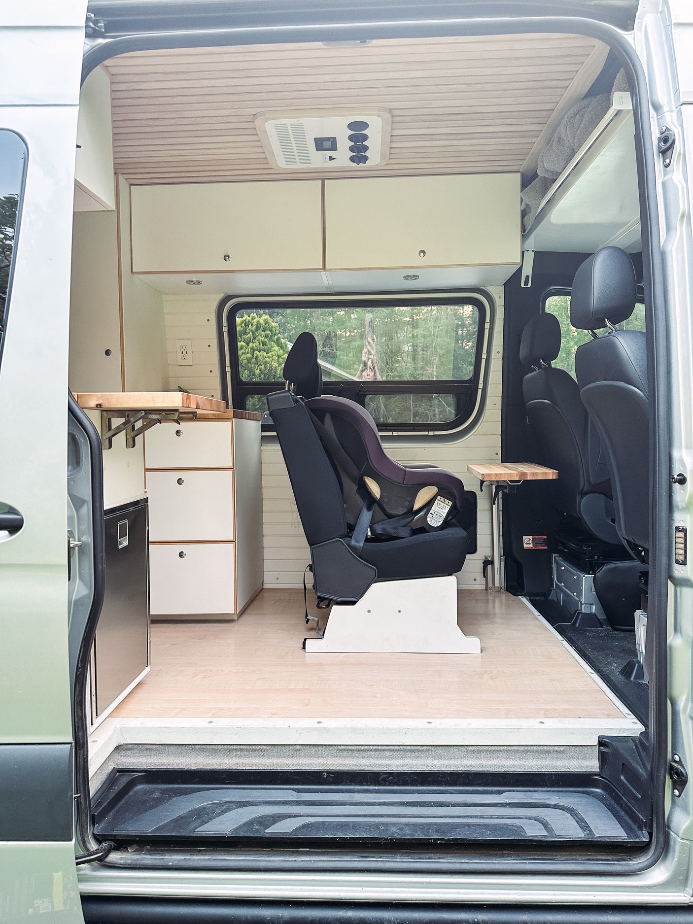 Inside an RV rental: a family-friendly camper van with child car seat, kitchenette, and passenger seating for road trip comfort.