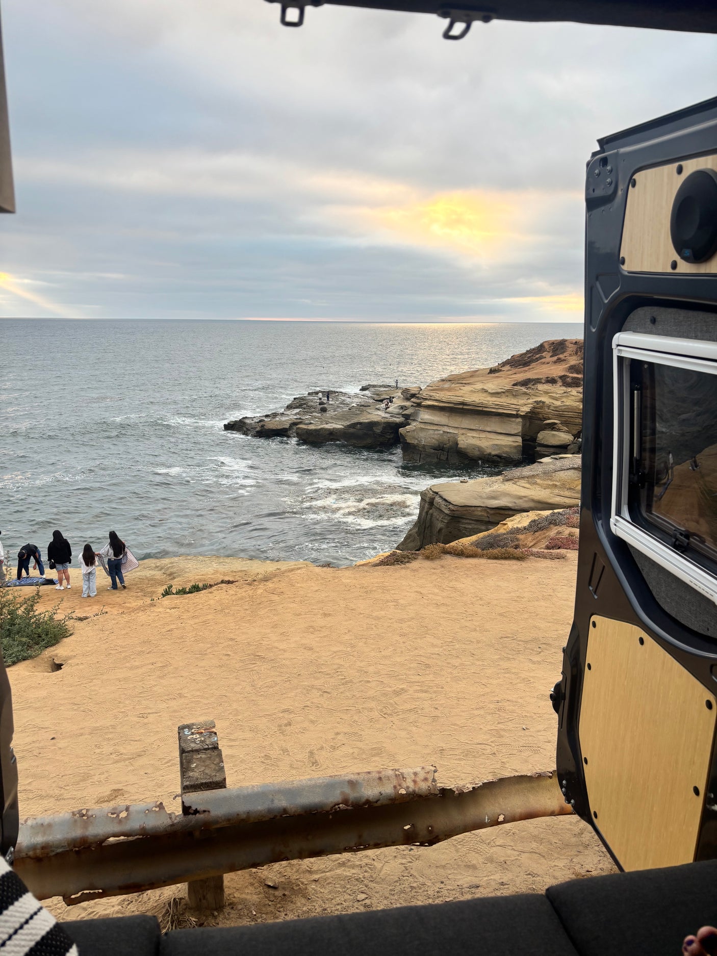 Ocean view from an RV rental, capturing coastline, beachgoers, and a faint rainbow. Perfect for van life adventures!