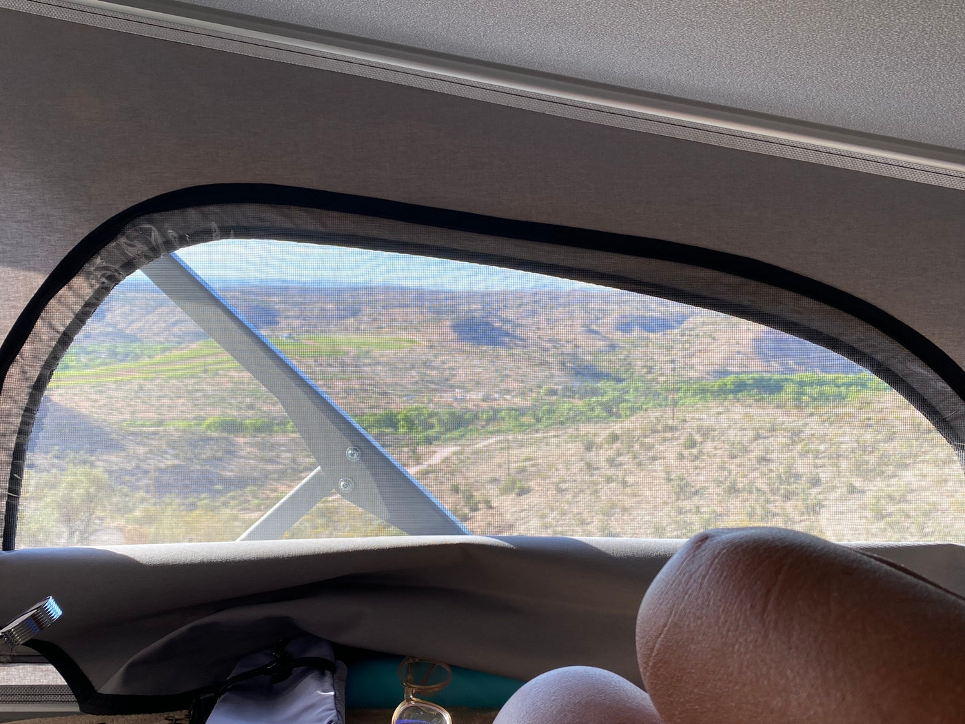 Relaxing in an RV rental, legs propped, viewing a vast desert landscape through the screened window. — photo 8