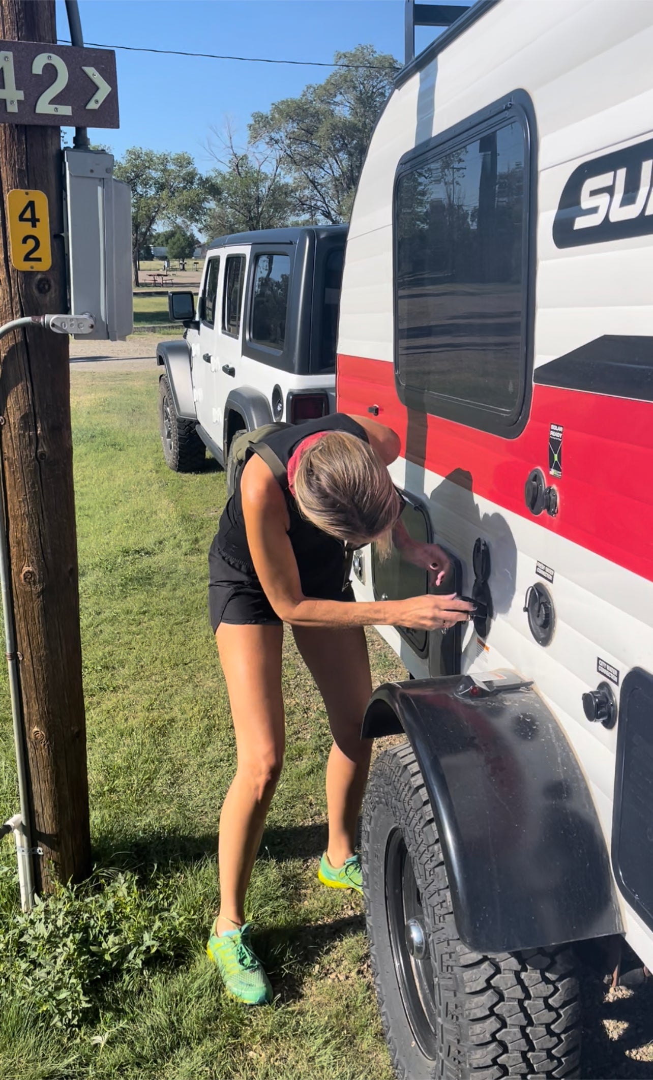 Connecting an RV rental at campsite 42. Woman ensures fresh water for her trip.
