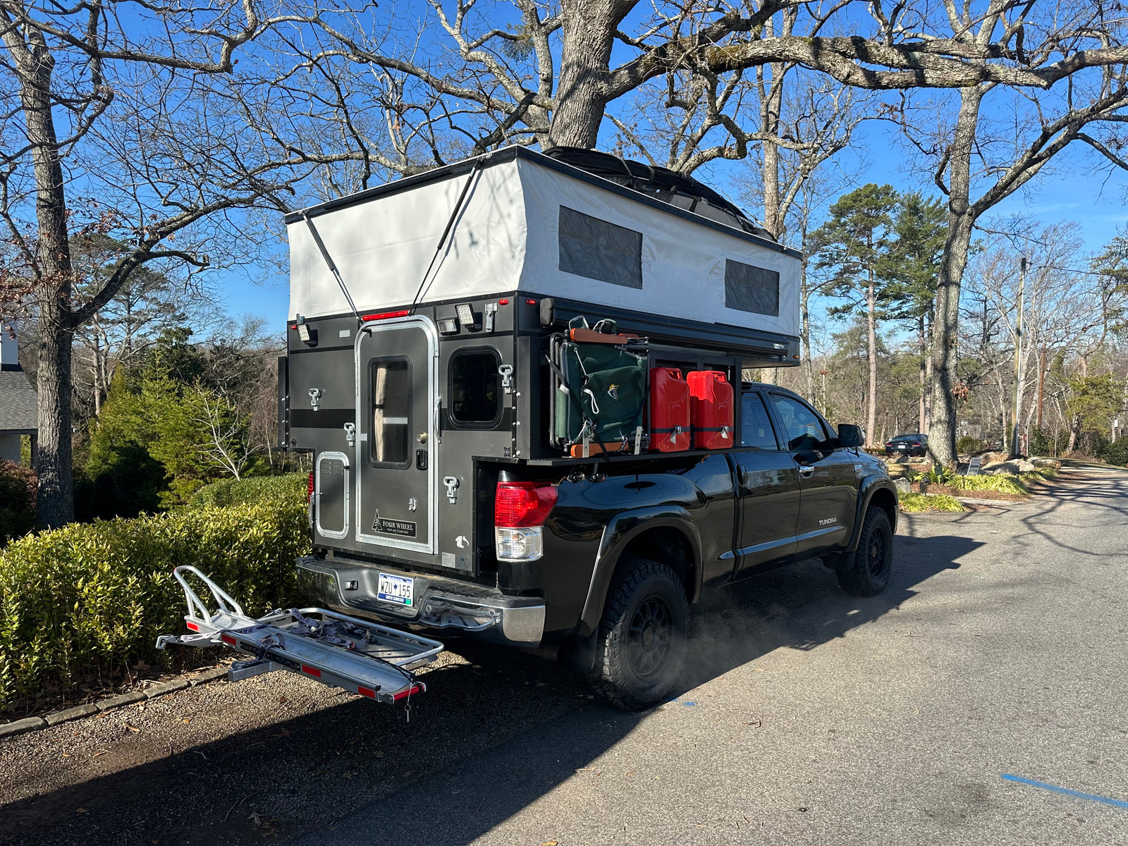 Explore more with this truck camper RV rental. Black Toyota Tundra with pop-up overland rig & gear.