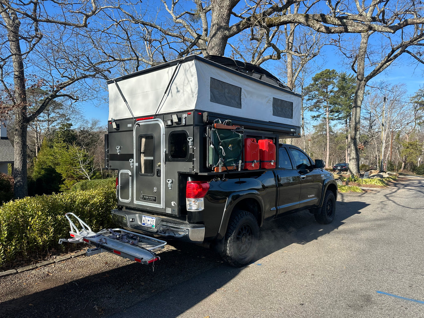Explore more with this truck camper RV rental. Black Toyota Tundra with pop-up overland rig & gear.