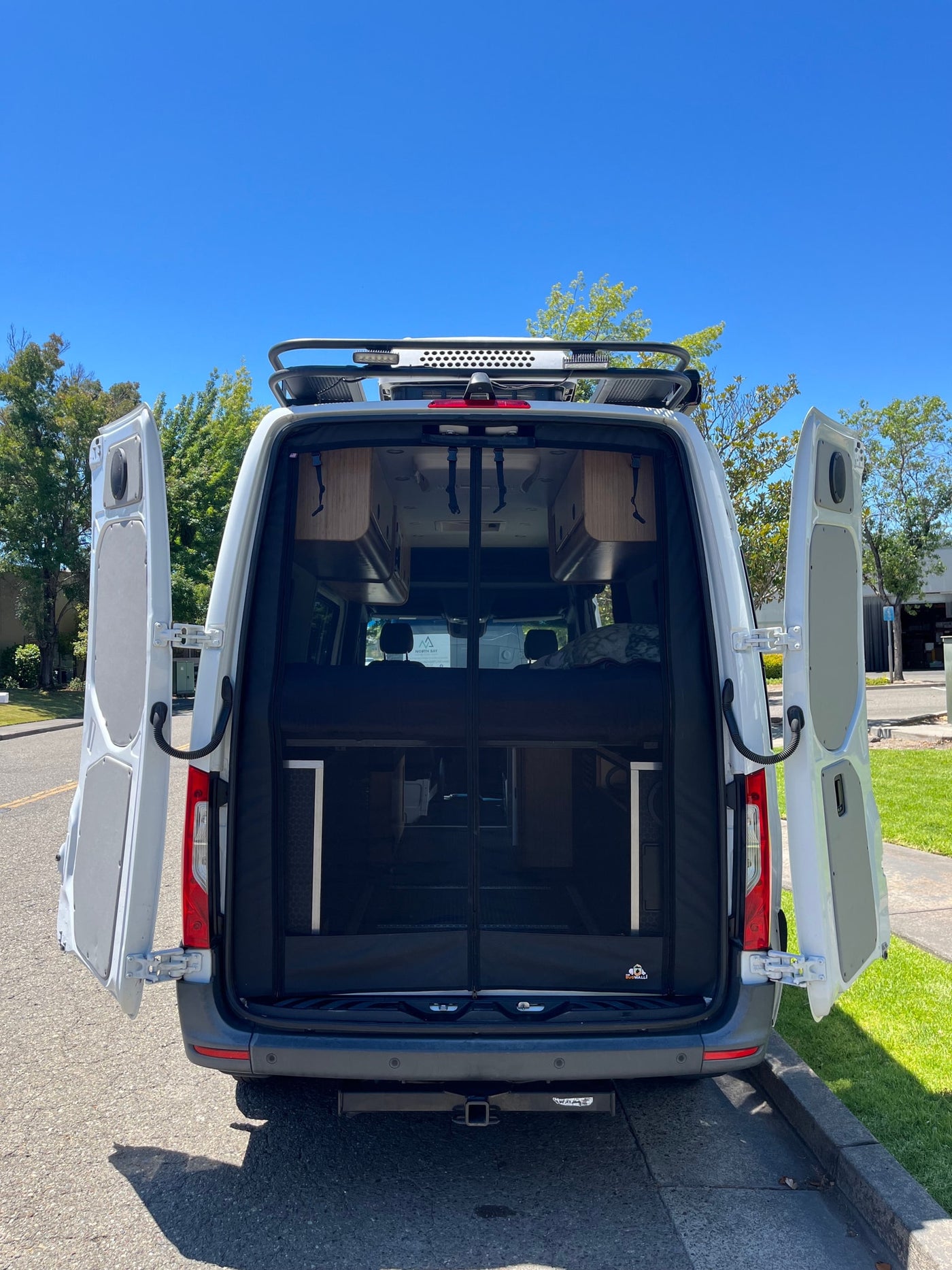 White camper van with open rear doors, showing an interior bug screen and living space. Ideal for RV rental getaways. — photo 4
