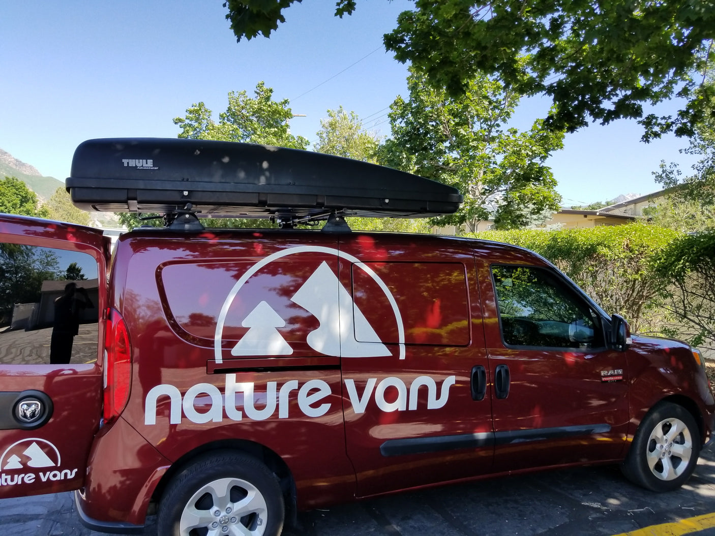 Maroon 'nature vans' van with a Thule roof box, ideal for RV rental adventures.