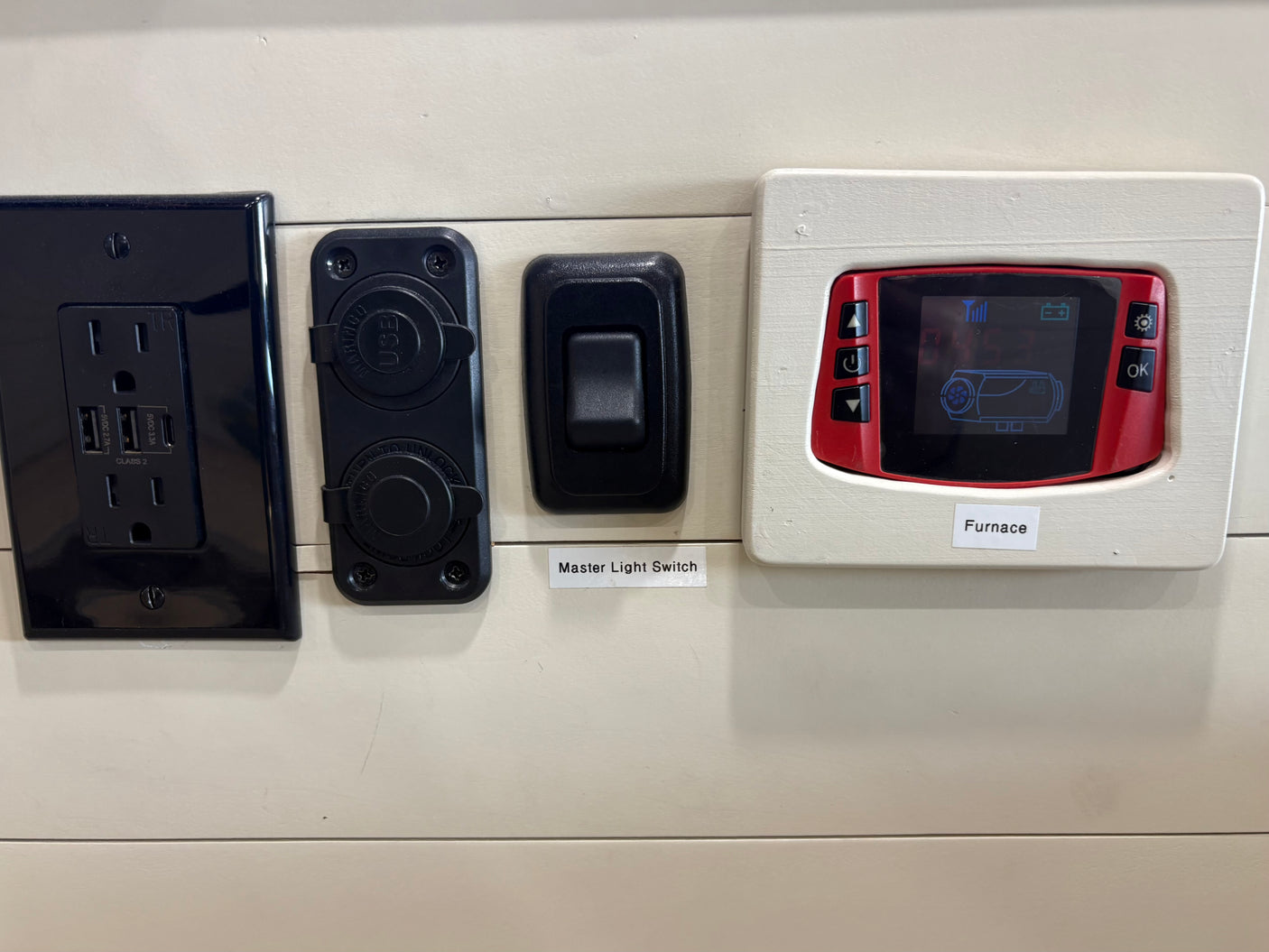 RV rental controls: electrical outlet with AC and USB, additional 12V USB ports, master light switch, and a digital furnace control panel.