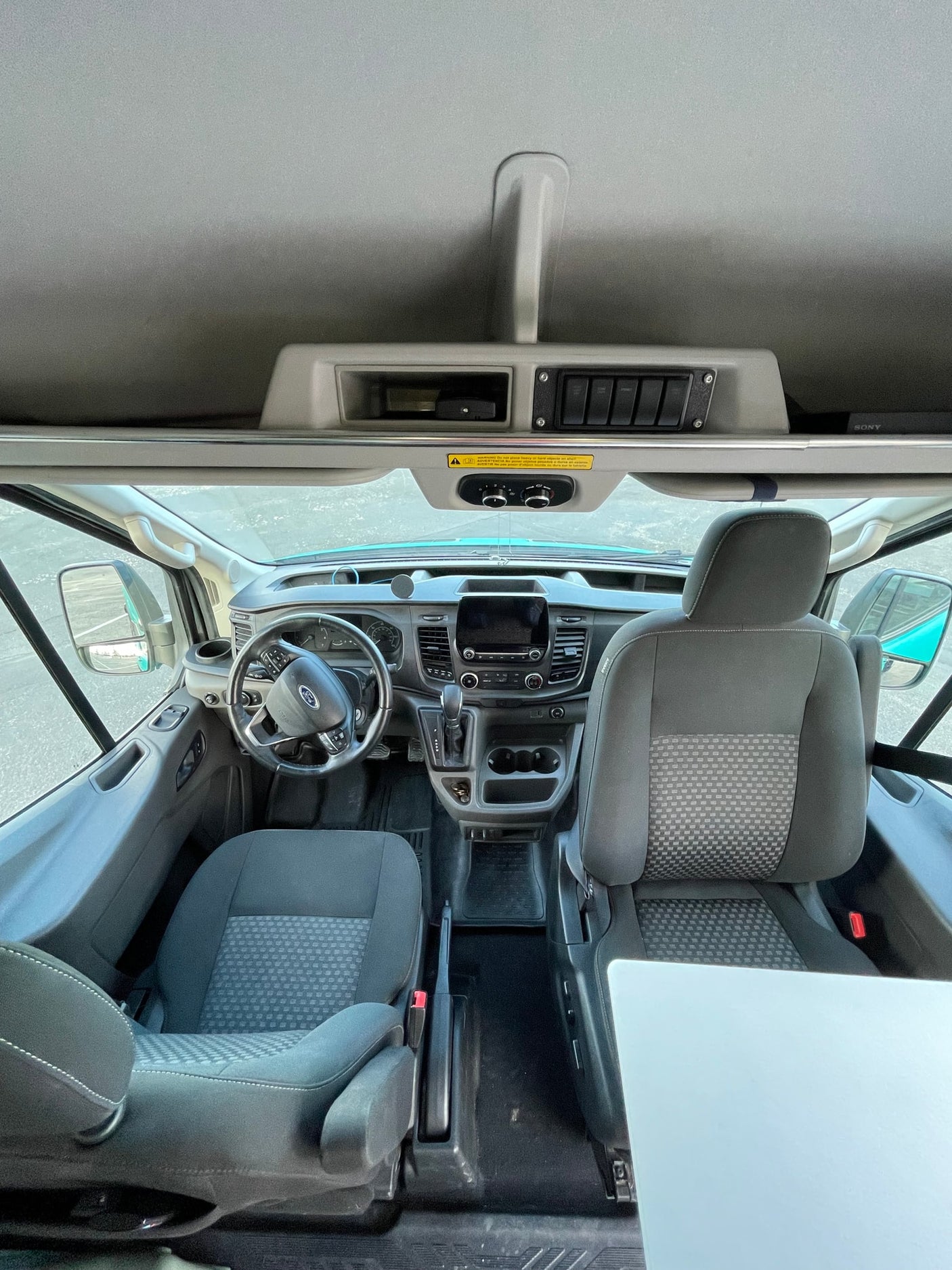 Spacious Ford rv rental cab interior, showing dashboard, steering wheel, comfortable seats, and overhead storage area.