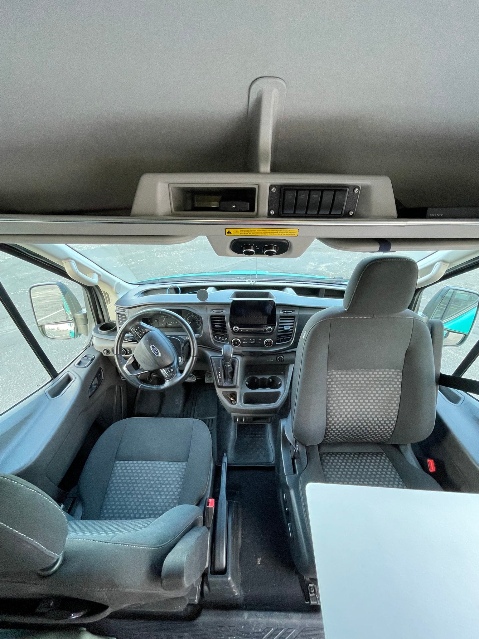 Spacious Ford rv rental cab interior, showing dashboard, steering wheel, comfortable seats, and overhead storage area.