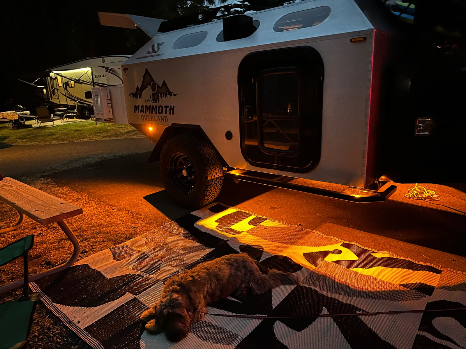 features an illuminated outdoor kitchen setup. Ready for adventure!|Night camping setup: SUV