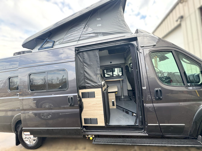 Pop-top rv rental with open side door revealing its compact living area, complete with a table and seating.