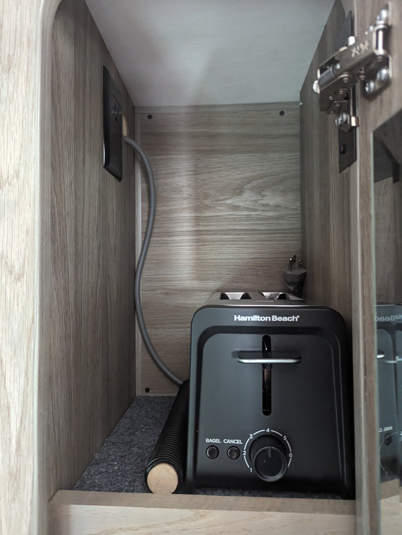 Hamilton Beach toaster neatly stored in an RV rental cabinet, ready for use with a nearby outlet.