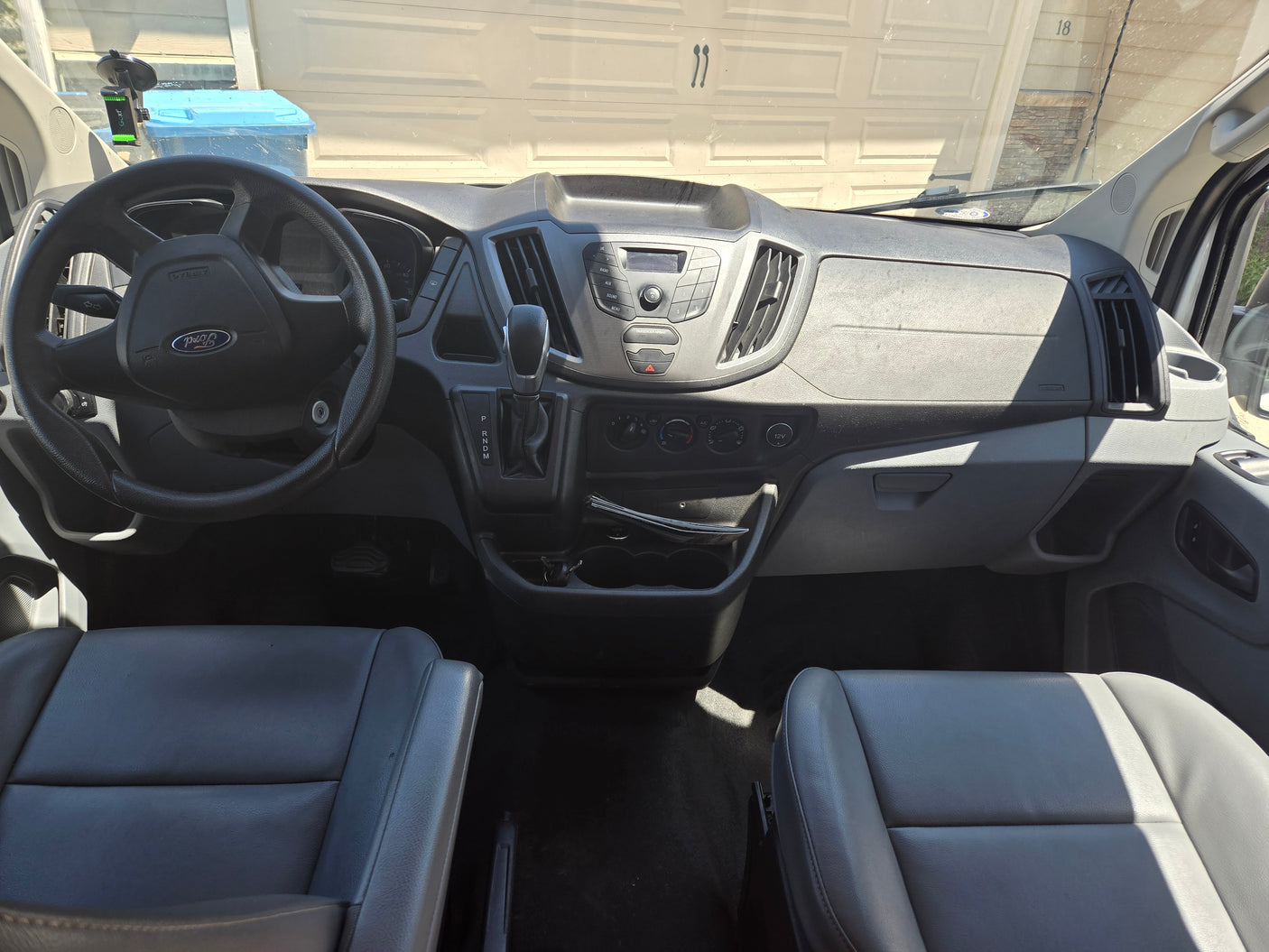 RV rental van's front cabin: Dashboard, steering wheel, and front seats clearly visible from the passenger perspective.