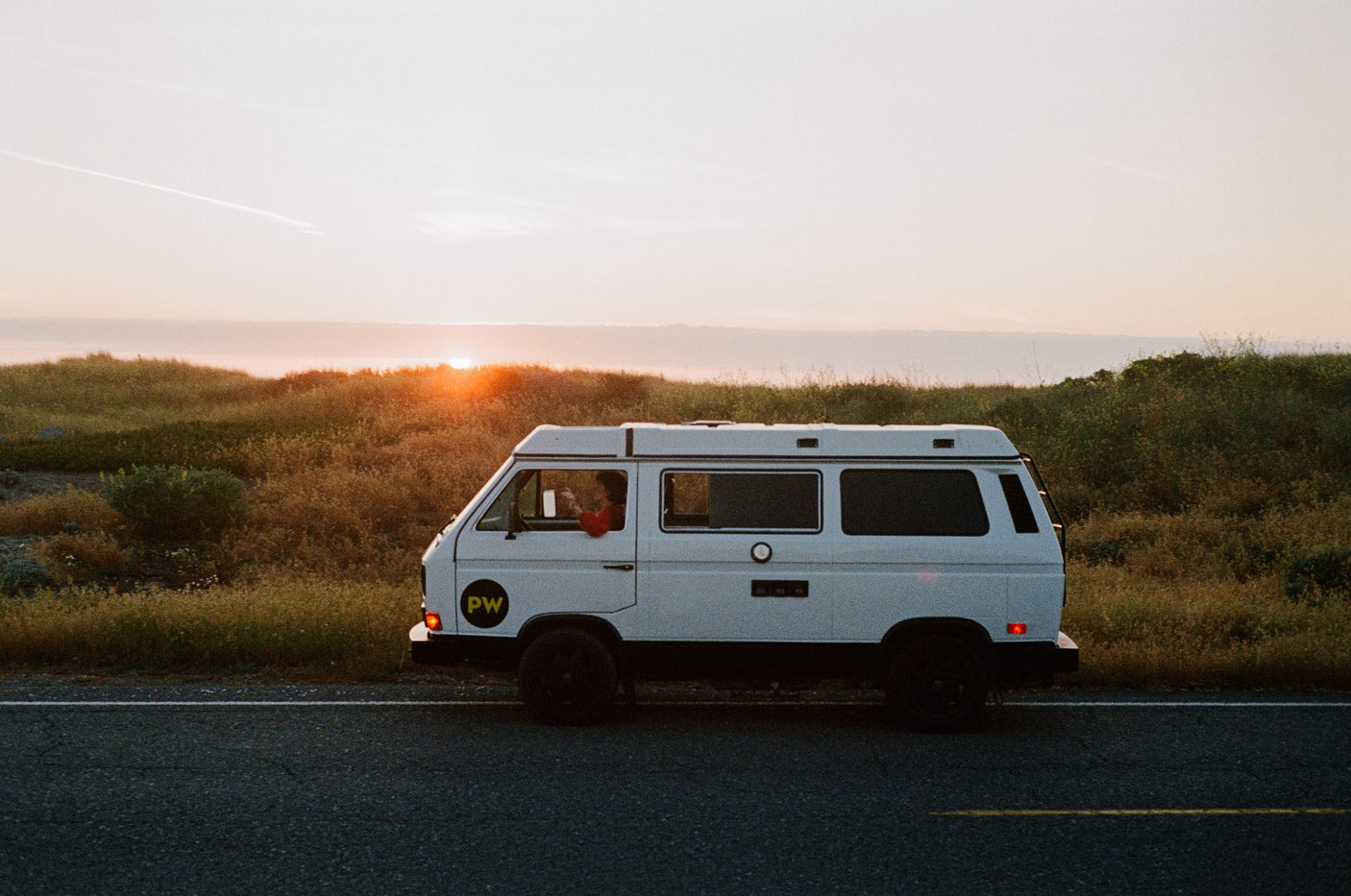 White camper van parked on a road at sunset. The perfect rv rental for a scenic road trip adventure.