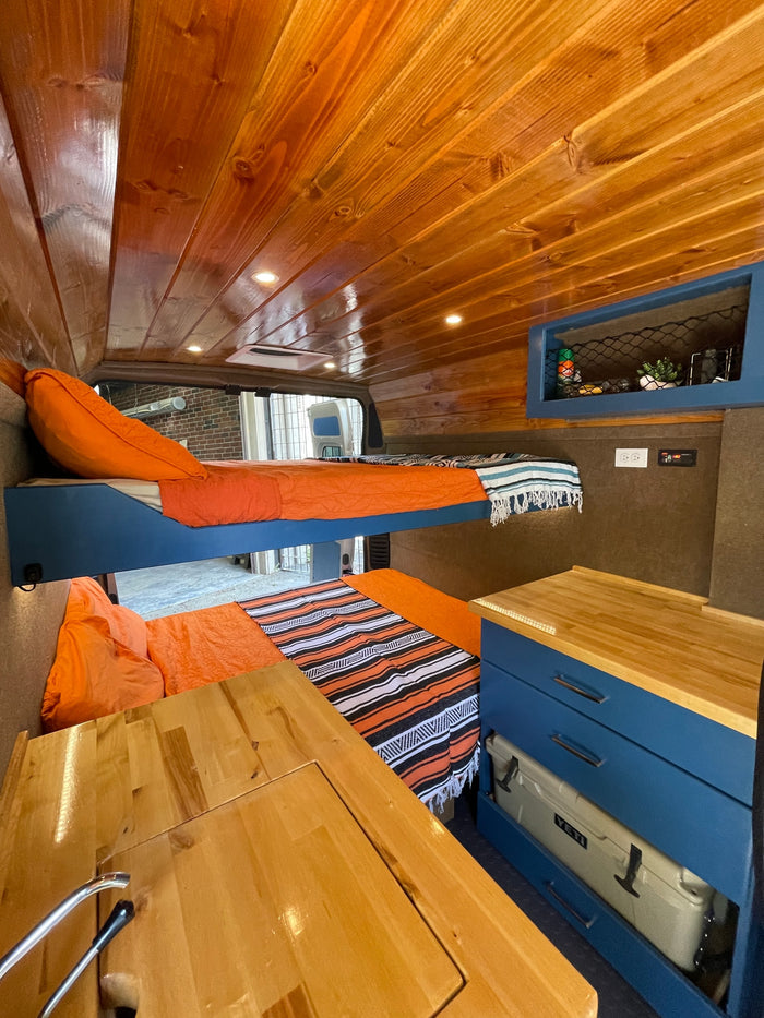 showcasing its unique camper van interior with blue cabinets and wood ceiling.|Explore this RV rental's comfy interior: wooden ceiling