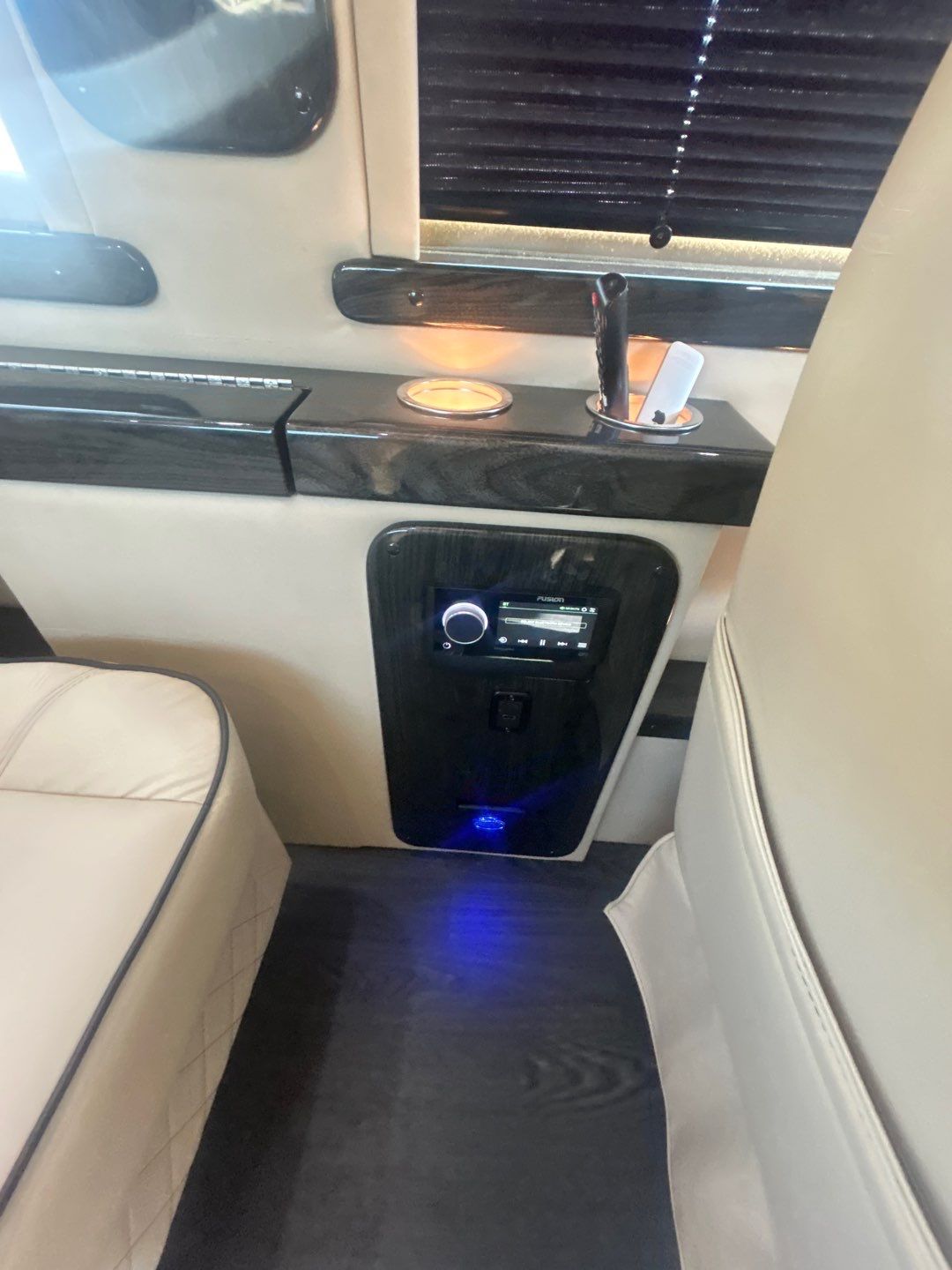 Luxury RV rental interior: a dark wood console with glowing infotainment controls, lit cupholders, and plush beige seating.