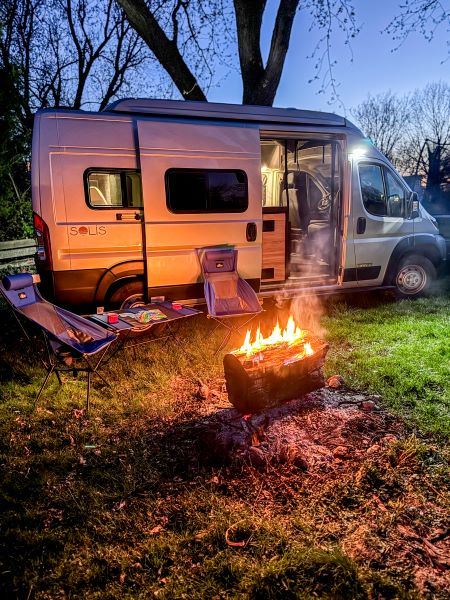 ready for travelers.|Silver Solis camper van parked by a serene lake on a sunny day. Ideal RV rental for outdoor adventures!|Enjoy your RV rental adventure!|An RV rental's open back doors with a mesh bug screen reveal the interior camping setup outdoors.|RV rental floor plan: Camper van layout with sofa/bed