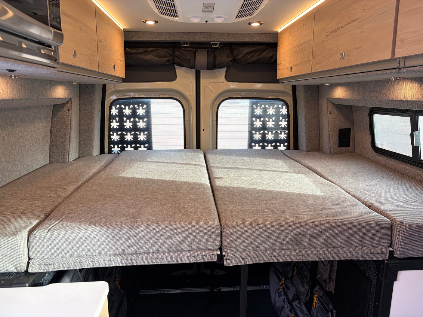RV rental interior: a plush bed, overhead cabinets with lighting, microwave, and under-bed storage for your travels.