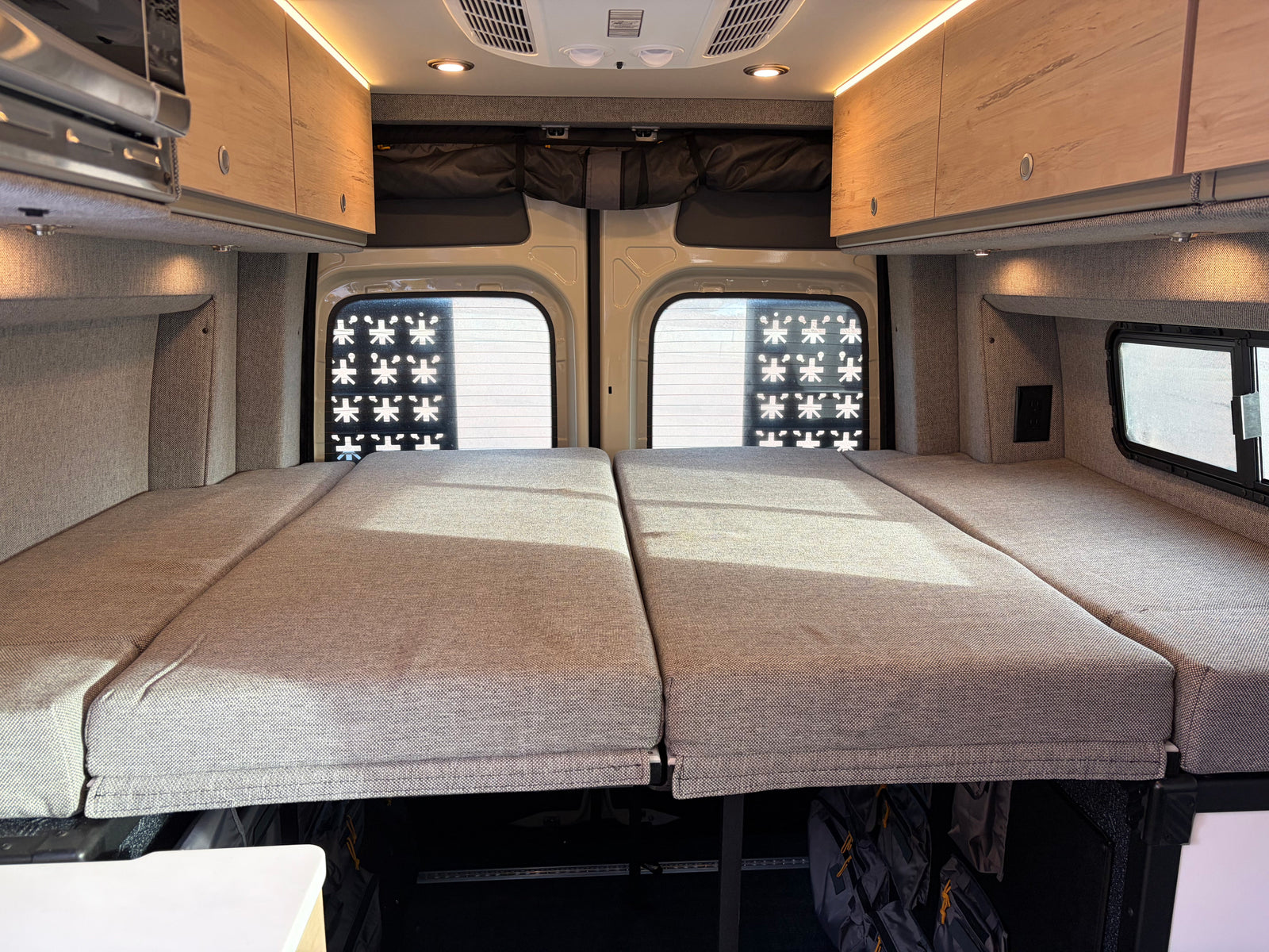 RV rental interior: a plush bed, overhead cabinets with lighting, microwave, and under-bed storage for your travels.