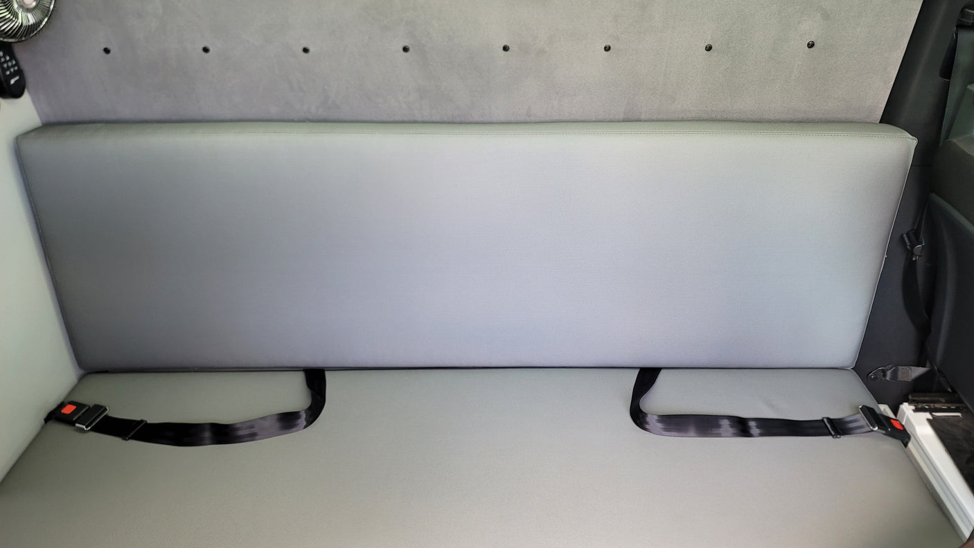 RV rental van interior: Gray upholstered bench seat, convertible to bed, with visible safety seatbelts.